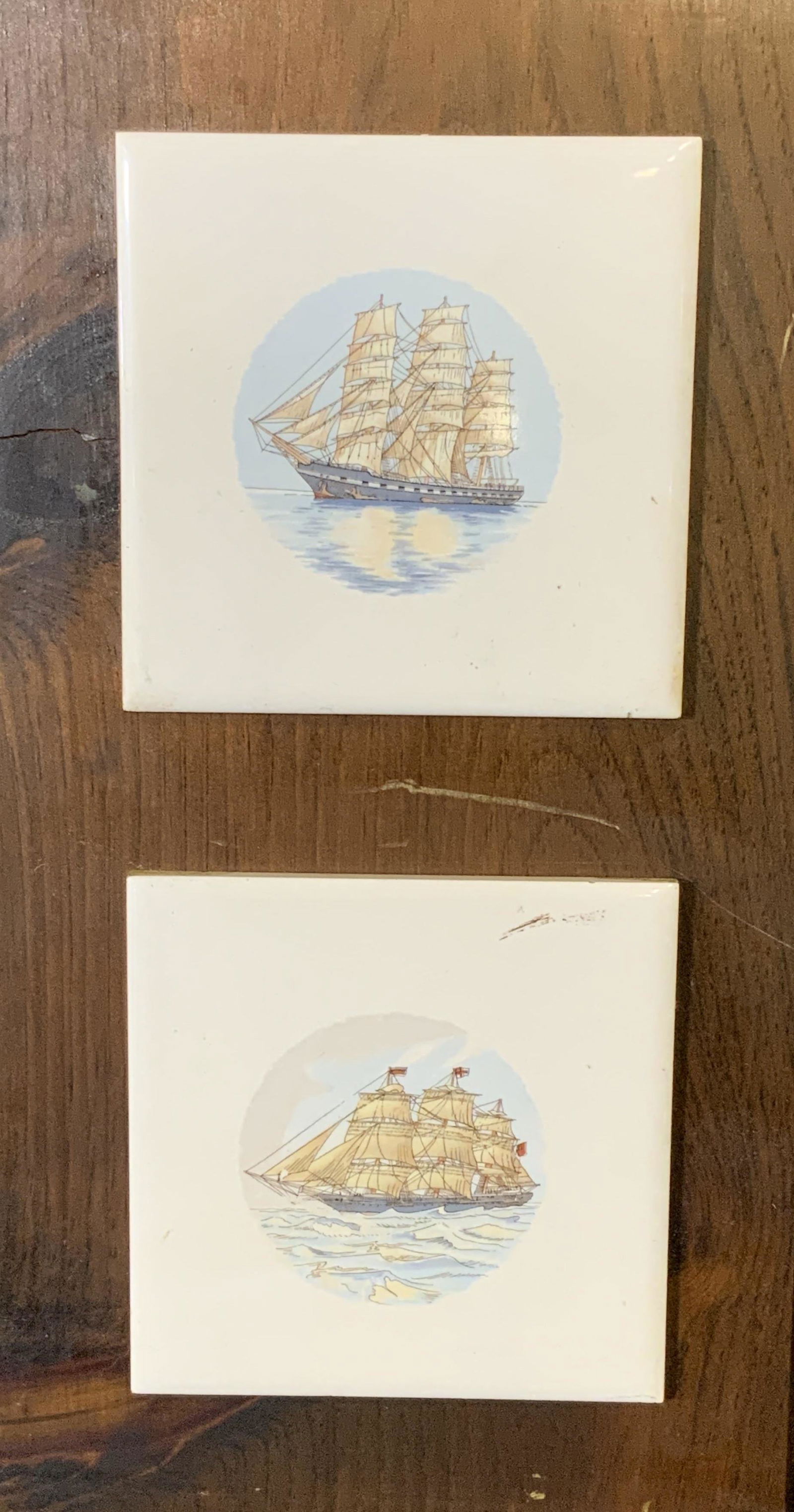 Pair Ship Tiles Mounted on Wood Panels: Pair ship tiles mounted on wood panels, each panel has two tiles mounted to them, each tile has a depiction of a ship at sea, panel made of a dark stained wood with a hook to the upper border, both pa