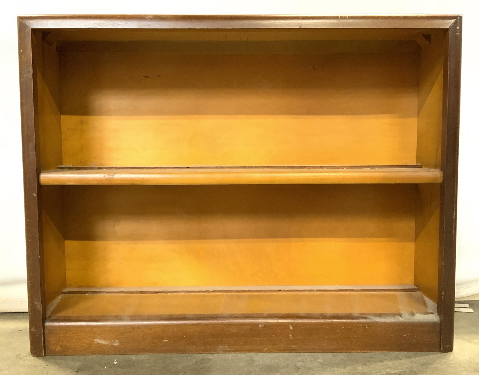 Vintage Low Wooden Bookshelf Bookcase: Bookshelf is wooden and vintage. Piece has 1 shelf area in center. Bookshelf has a light brown beige tone. Piece measures approx 26 inches tall 33 inches long 8 inches deep. Property of multi generati