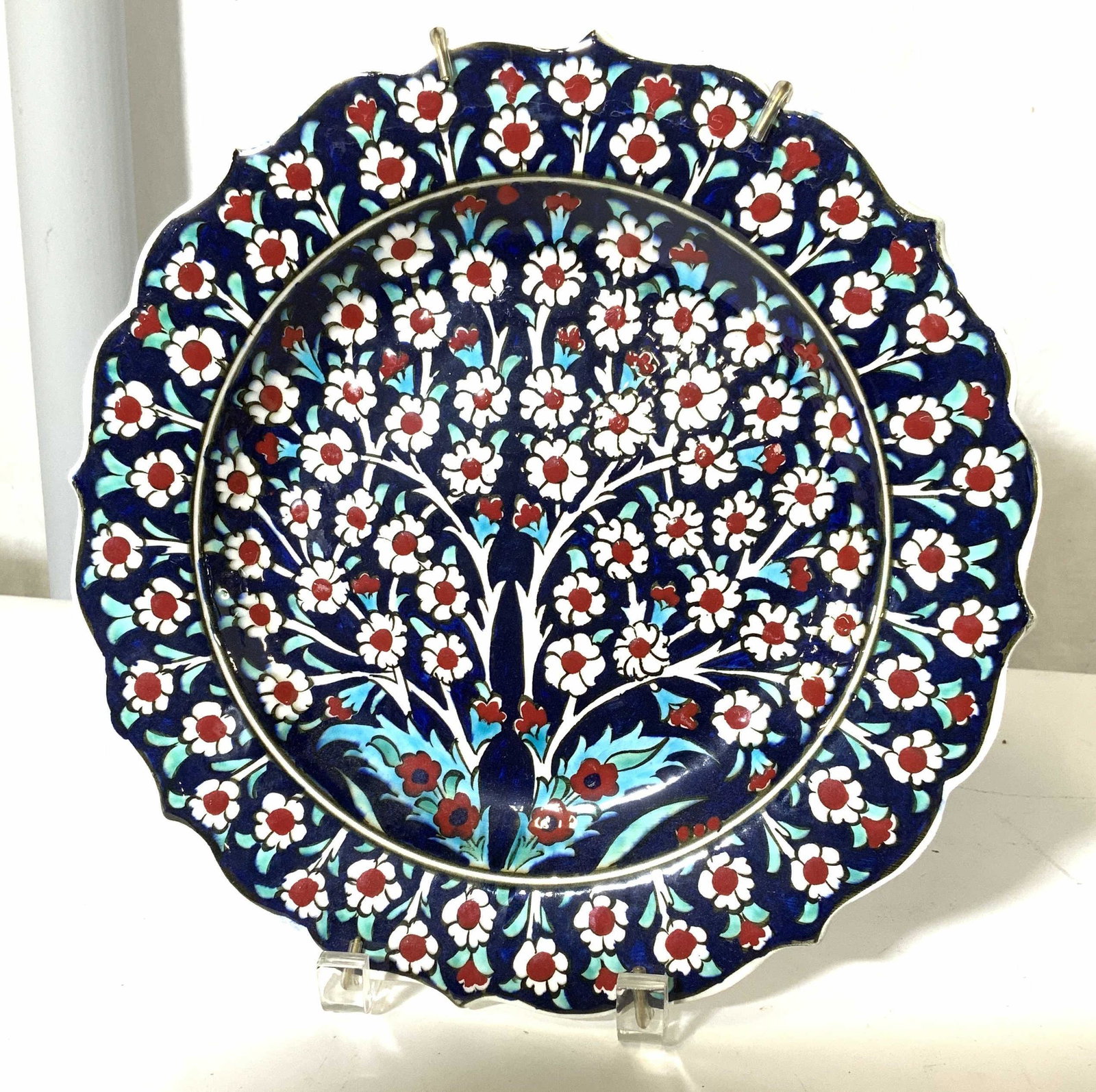 Hallmarked Hand Painted ceramic Wall Plate: Vibrant plate, hand painted, reticulated white daisy decor with red flower head on navy blue glaze. Scalloped rim and brass wall hanger. 10.25 in. Property of multi generation Brooklyn Collector’s E