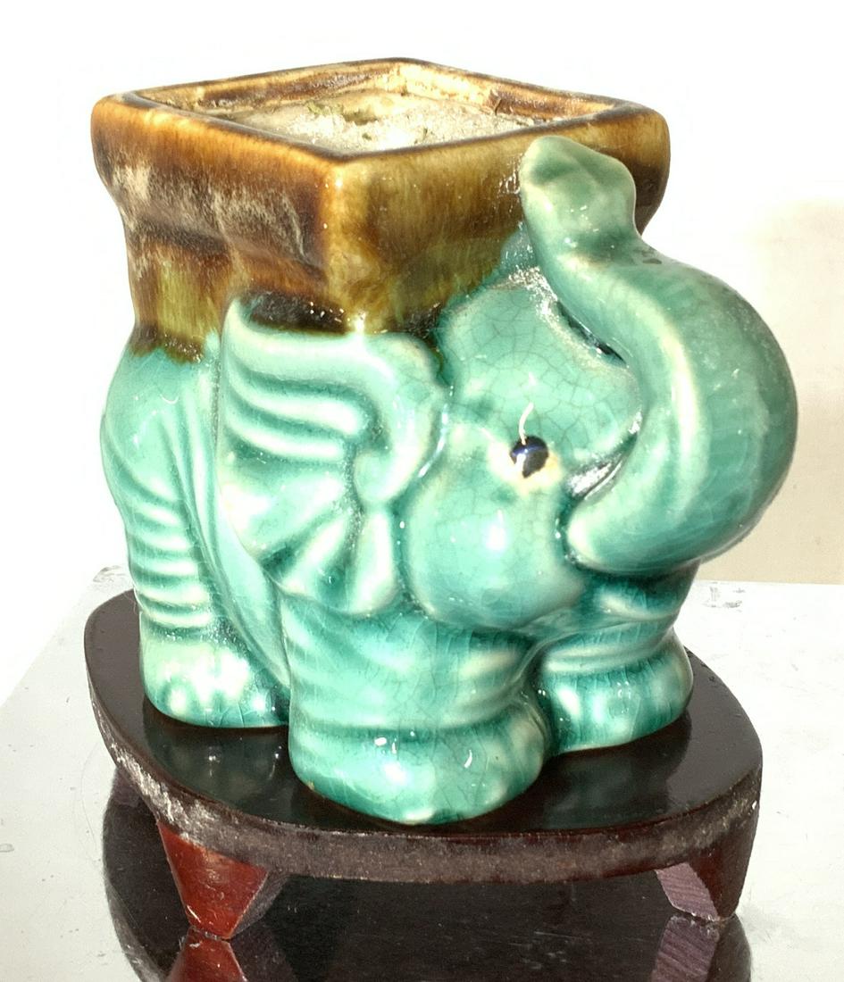 Collectible Asian Elephant Vessel on Stand: Good luck elephant with trunk in upright position, Glazed a sea foam green, underside has label Made in China. Vintage crazing. cachepot, vase or desktop accessory. Comes with lacquered stand. 5 in. W