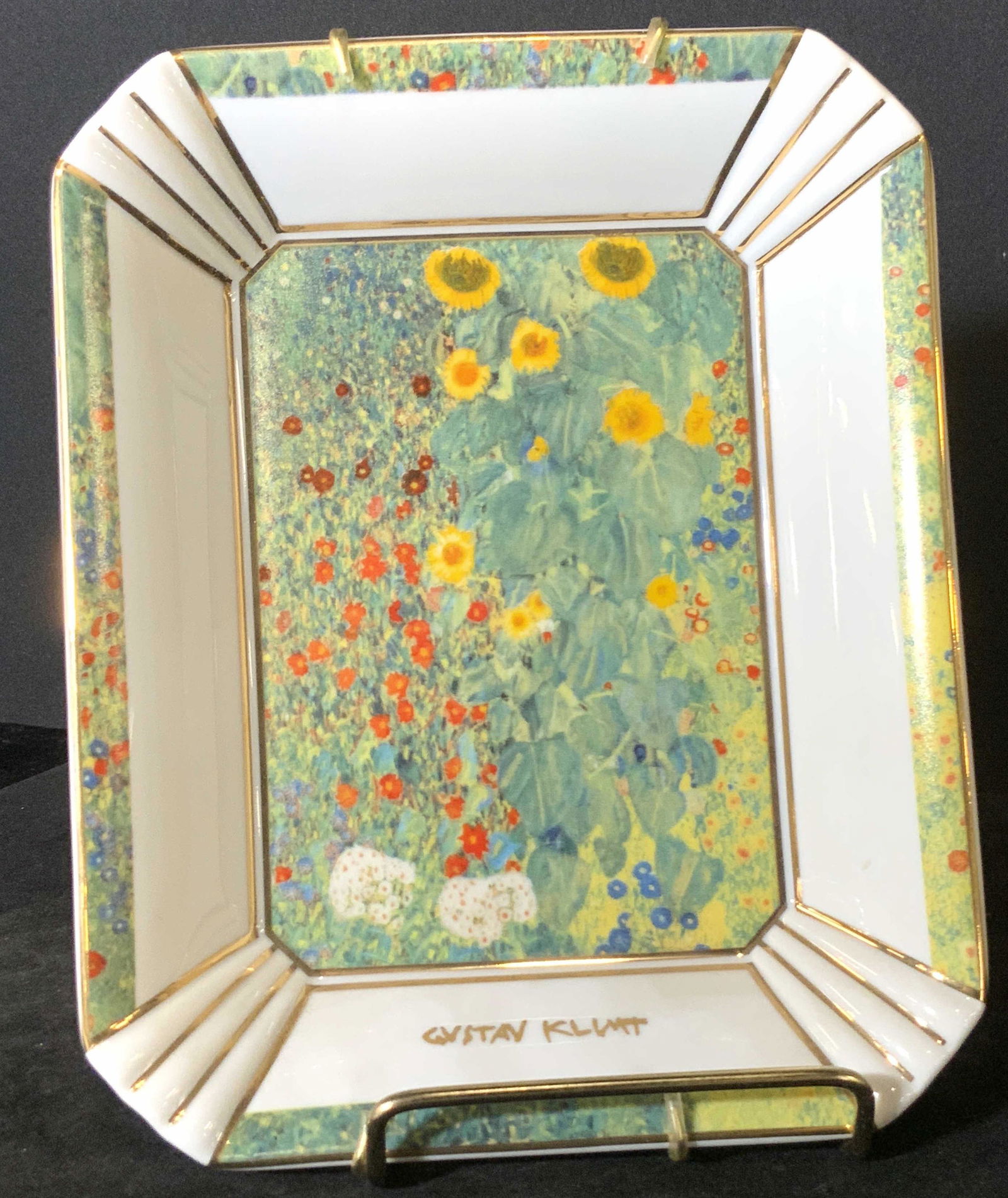 GOEBEL Signed German Porcelain Gustav Klimt Dish: A square form dish with painted florals and gilt line work. Beneath the painted florals on the obverse reads: GUSTAV KLIMT. The reverse has gold tone metal hardware hanging accessories. The reverse is