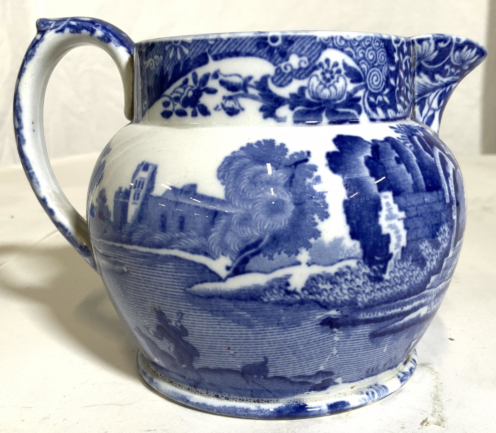 COPELAND SPODE Porcelain Creamer Dish: Underside is marked COPELAND SPODES ITALIAN ENGLAND. Piece is white with blue toned depiction of village in addition to floral, leaf & vine detail. Piece measures approx 3.5 inches tall 5 inches deep 