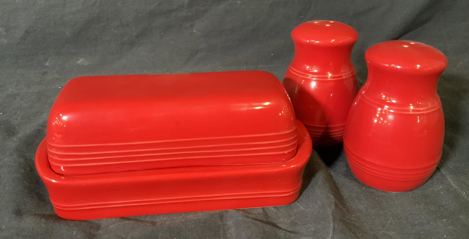 The Cellar Butter Tray And Salt & Pepper Shakers: The Cellar Butter tray and salt & pepper shakers, sticker to shakers and label to underside of tray reads ‘The Cellar’, all are colored red ceramics, shakers measure 4.25 inches at tallest point, 