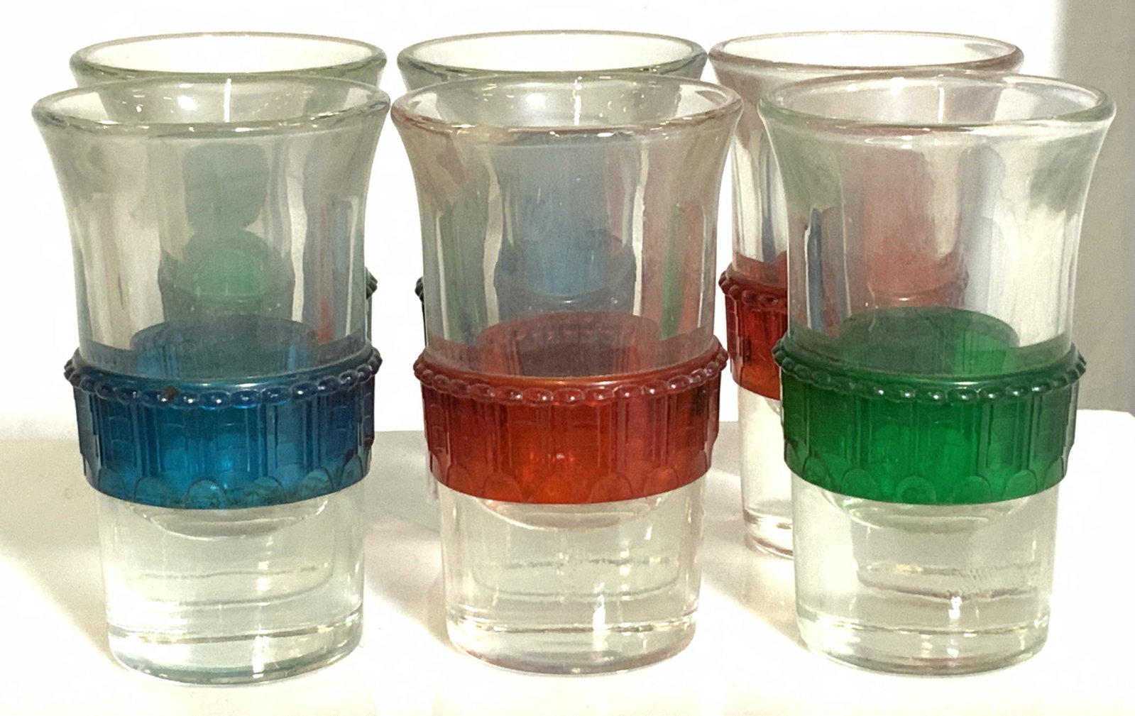 Set 6 Vintage Shot Glasses with Color Accent Band: Thick walled shot glasses with added exterior colored glass border. Red, green, and blue on clear glass. Measure 2.75 in. Tall. Bar ware, vintage shot glasses, mid century shot glass set, art glass, t