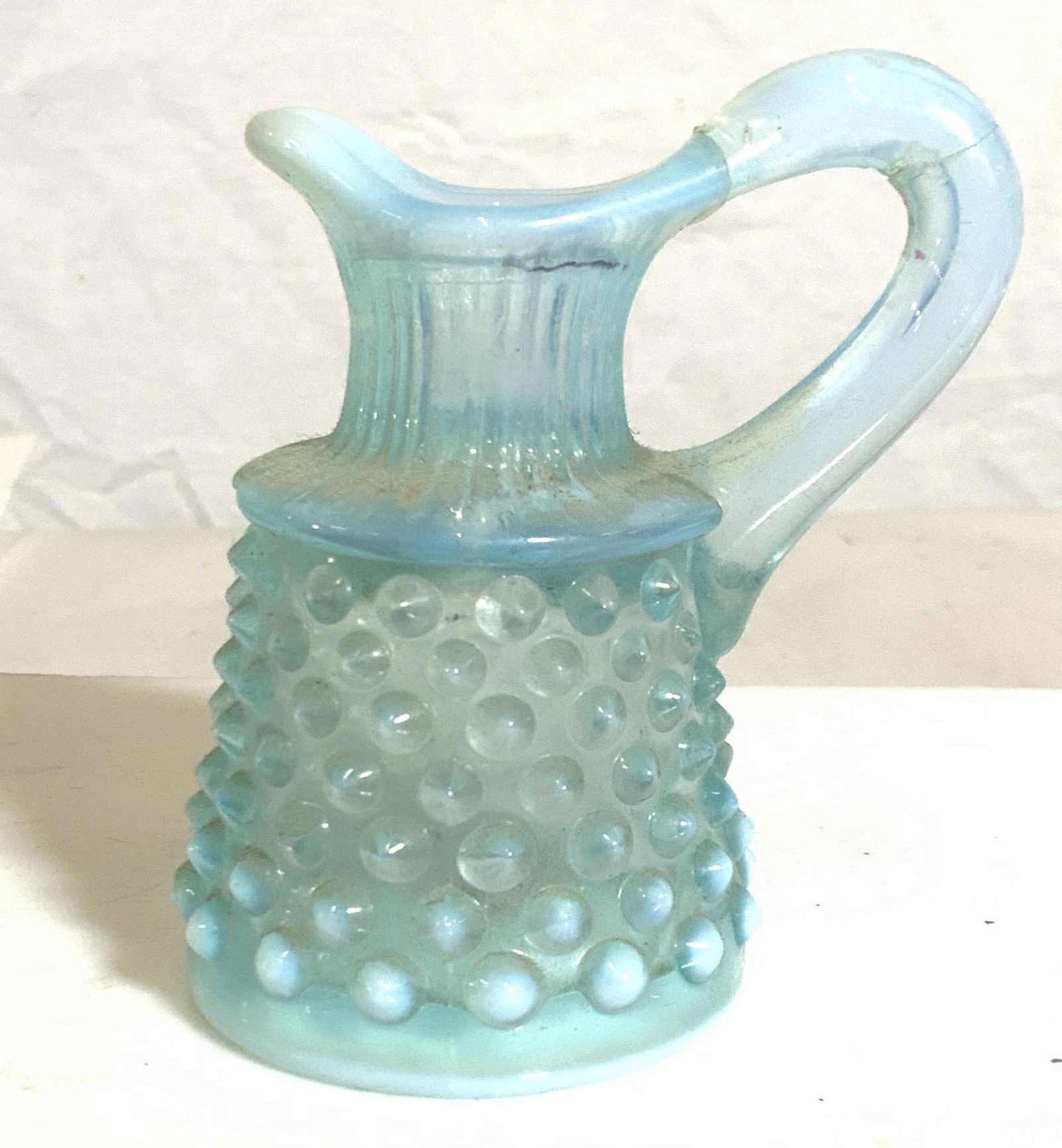 Mid Century Hob Knob Thick Sky Blue Vessel: Embossed decorative Hob knob vessel, use as a creamer, flower Bud vase, decorative accessory, pen holder, more. Made of molded glass, vintage, with a touch of milk glass to the sky blue. Handle has be