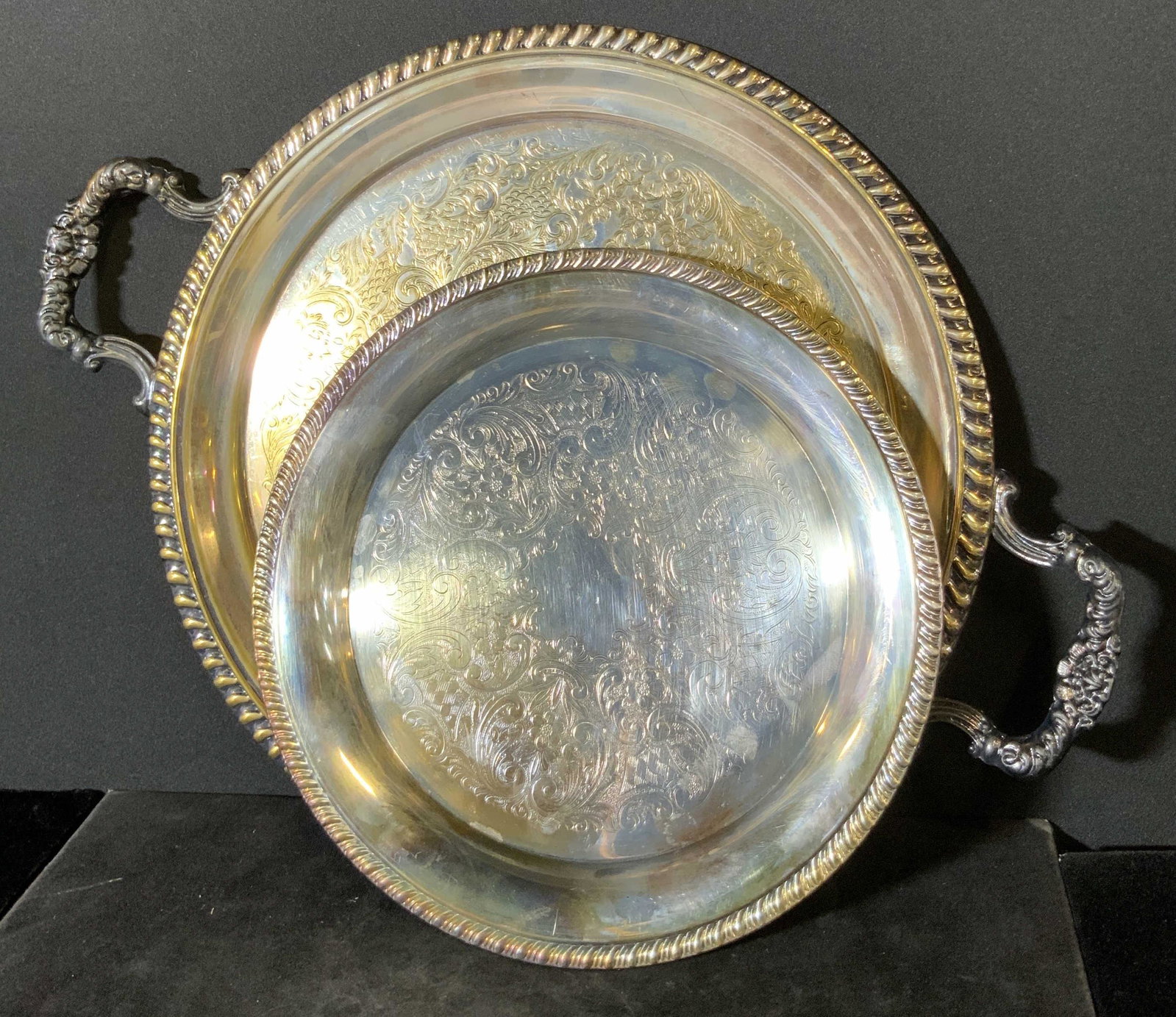 Lot 2 5TH AVE & LEONARD Silver Plated Trays: Two possibly vintage silver plated trays featuring embossed metalwork rims and etched centers. Victorian style. One piece has twin handles. One piece is larger than the other, has some gold tone wash 