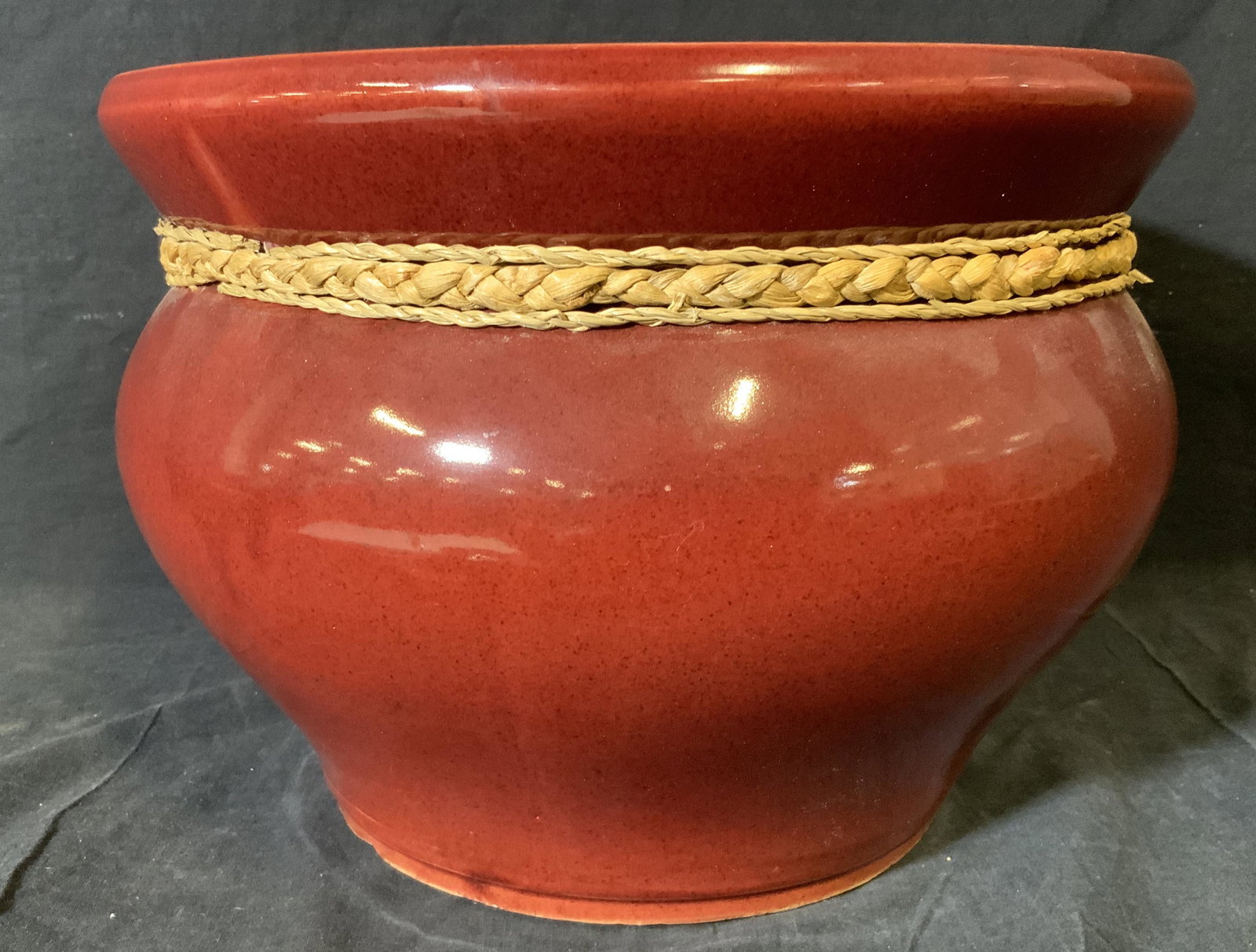 Ceramic Vietnamese Planter Cache pot: Ceramic Vietnamese pot, tag to underside of pot reads ‘Made in Vietnam’, surface of pot colored red with the interior remains creme, attached to the neck of the pot are three braided piece of rope