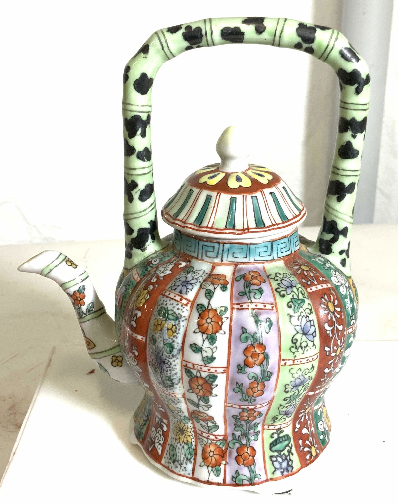 MMA DECORATIVE ASIAN TEAPOT, signed: A decorative piece, vintage , Hallmarked MMA, not for food use, decorative object only. Lidded teapot with square handle. Floral decor, rubber feet. 6.5 in. Ht, 6 in. W. Property of Multi Gerational B