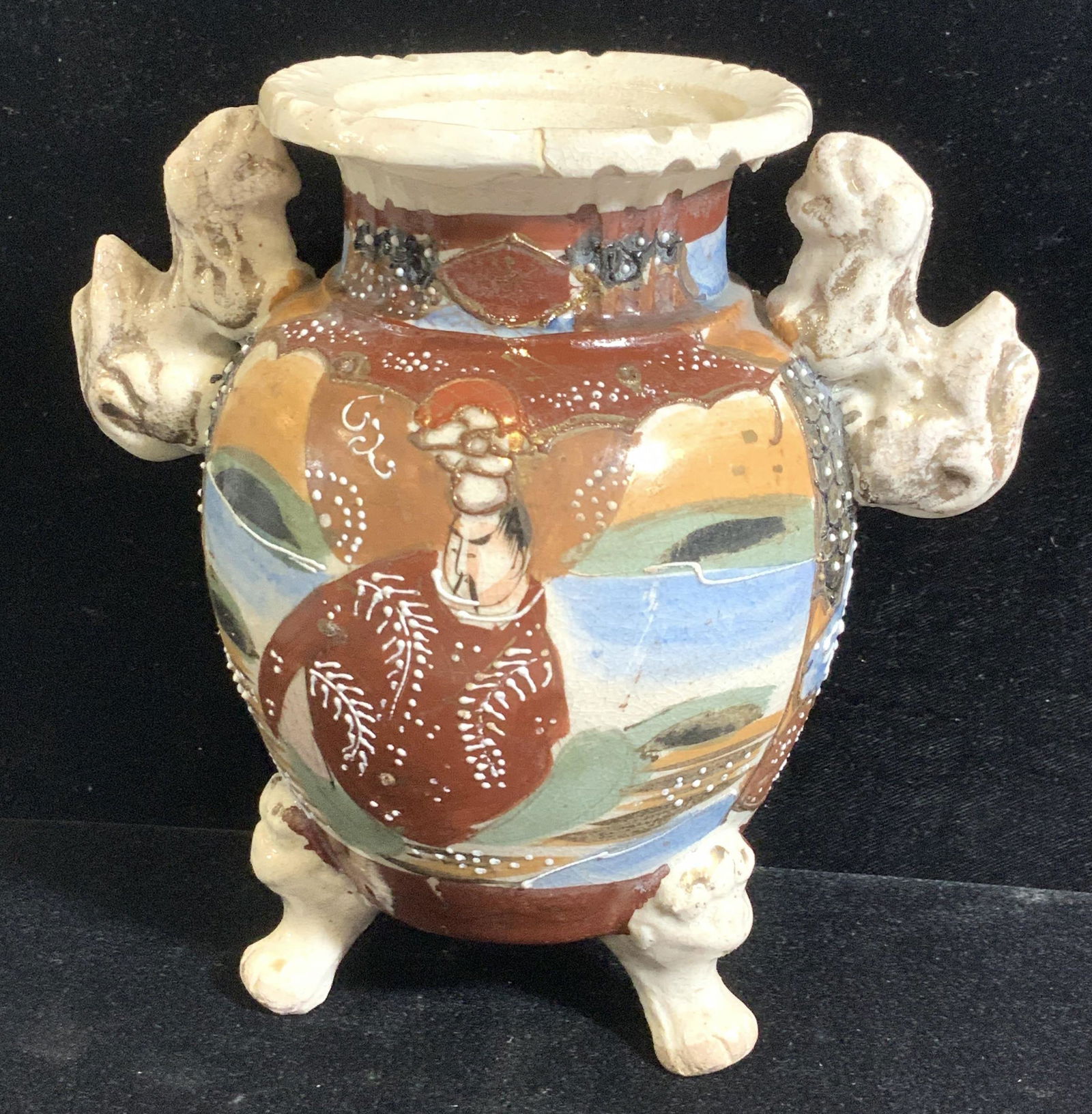Fu Dog Satsuma Hand Painted Ceramic Vessel: Hand painted, raised paint or vessel with Foo dog handles and foo dog face and paw feet. Depicts man on one side and 2 ladies on the other side. Repaired crack to rim. Paste up outline in gilt. Vintag