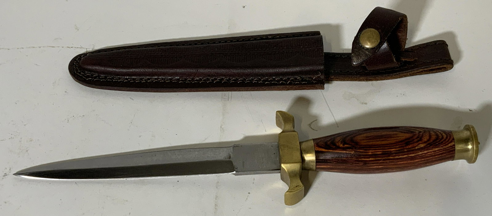 Wooden Handled Dagger and Leather Sheath: Wooden Handled dagger and leather sheath, stainless steel, blade marked ‘Stainless Pakistan’, full tang blade in dagger shape, comes with a brown leather sheath meant to be worn on a belt loop, bl