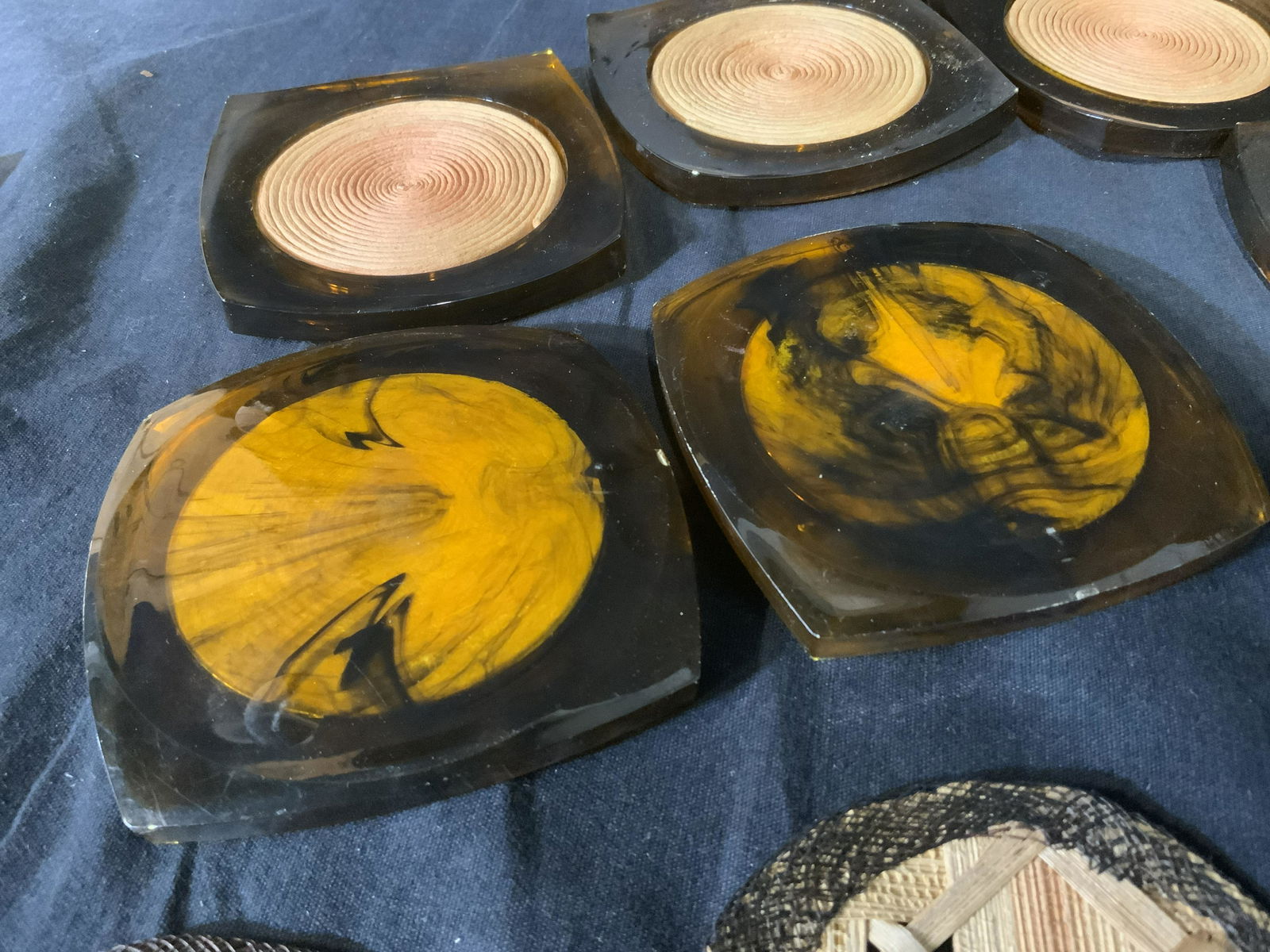 Lot 12 Vintage Coasters: Lot of twelve vintage coasters. Includes a set of eight and a set of four. The eight coasters appear to be crafted from plastic, possibly Bakelite, and a paper or fabric coil. The set of four is wood