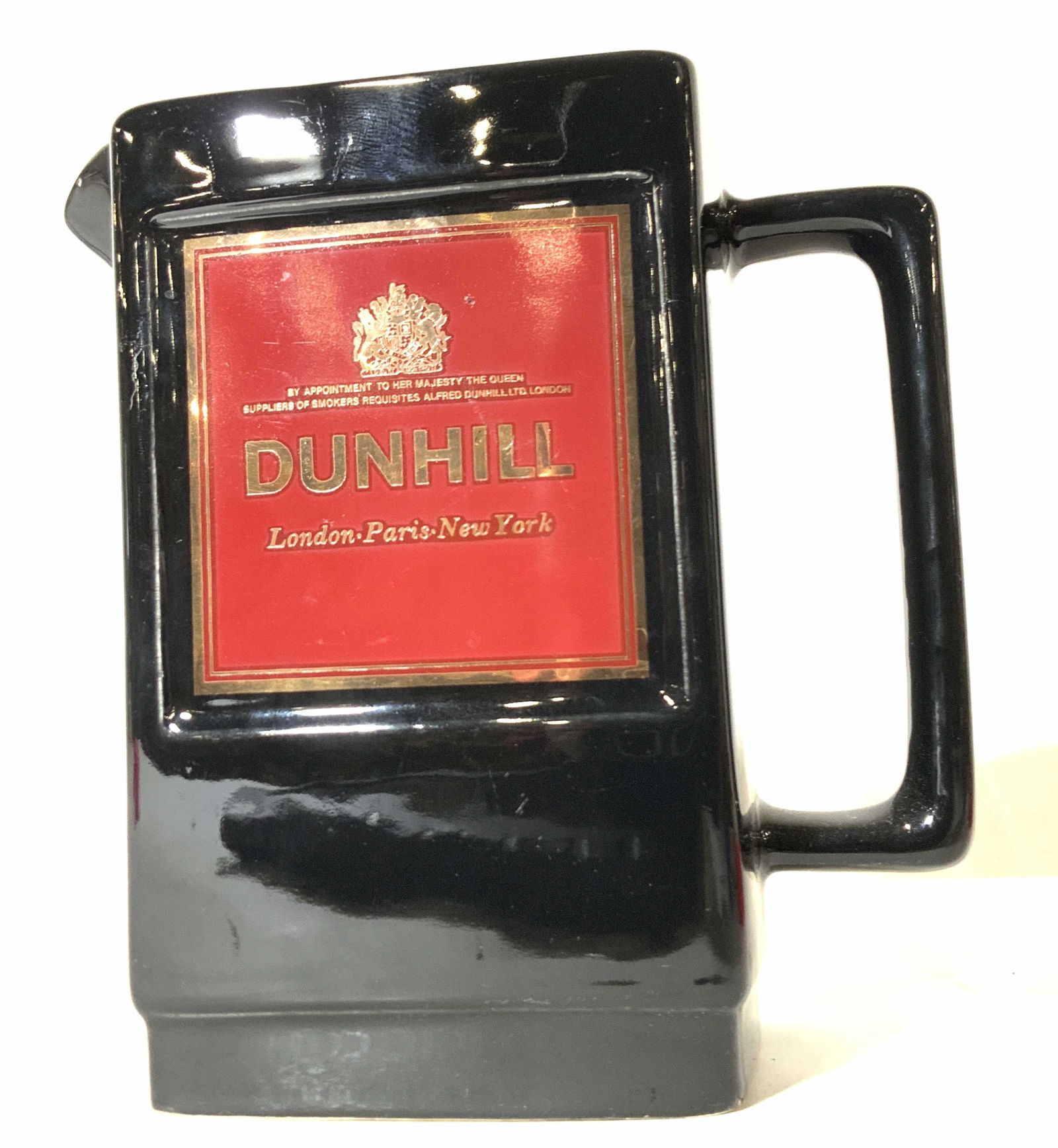 DUNHILL Wade English Porcelain Pitcher: A black, rectangular form porcelain pitcher. Thick walled porcelain. The piece has red square accents on both sides. Lettering within the square is gold toned and reads: DUNHILL, LONDON, PARIS, NEW YO