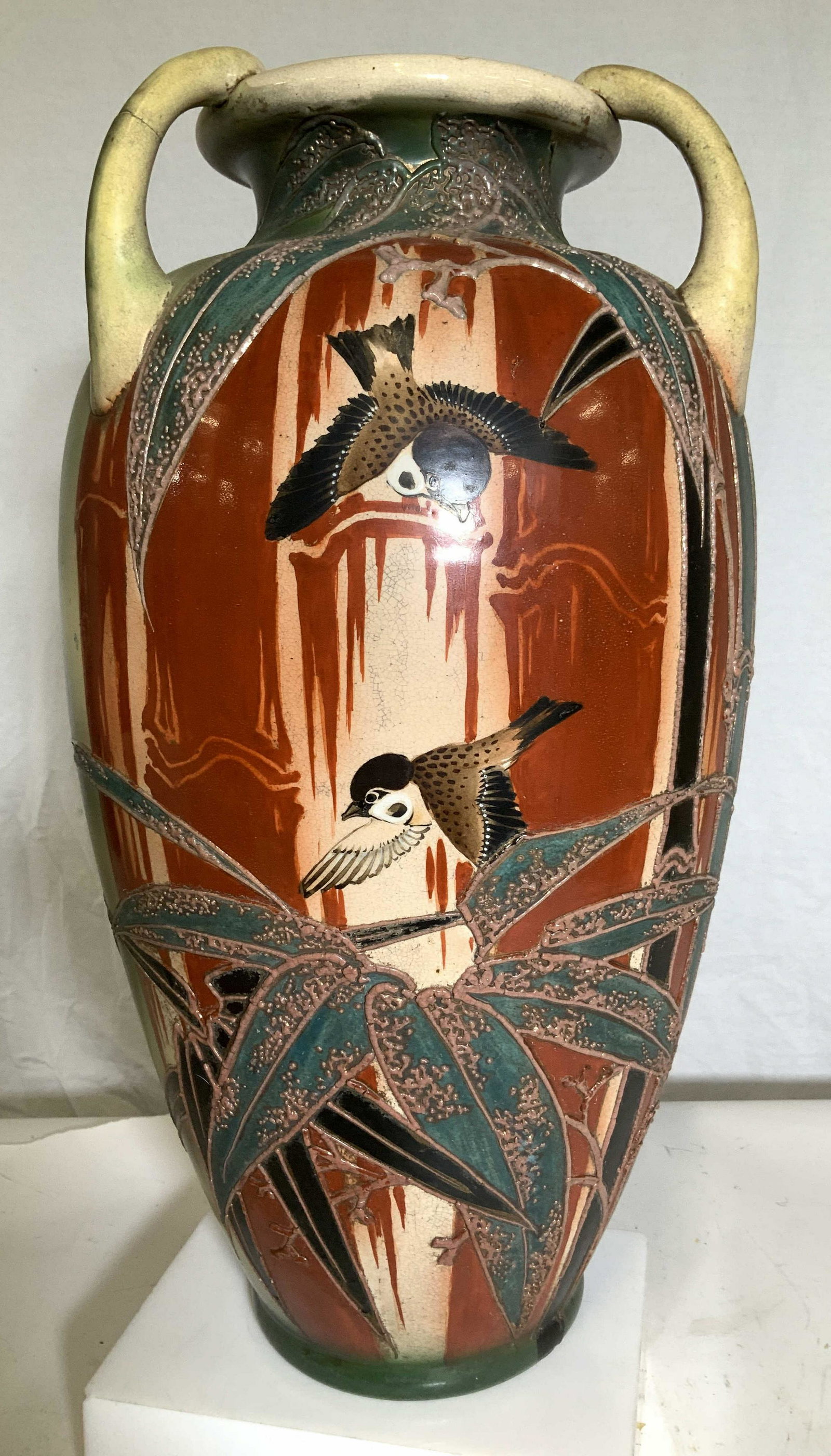 Floor Sized Ceramic Vase with Birds 18 in H: Paste Up painted design of two birds flying to tropical plants. 3 handle vase, repaired crack to one handle, subdued colored of green, rust, black, teal and brown. 18 in ht, 10 in. W. No marks, possib