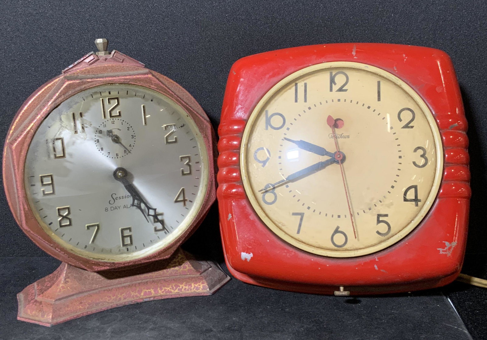 Lot 2 SESSIONS & TELECHRON Vintage Red Clocks: Two collectible vintage red hued clocks. The clocks are signed TELECHRON AND SESSIONS. All brands appear on the clock faces. One clock is circular in shape, stands to be displayed on a tabletop. The o