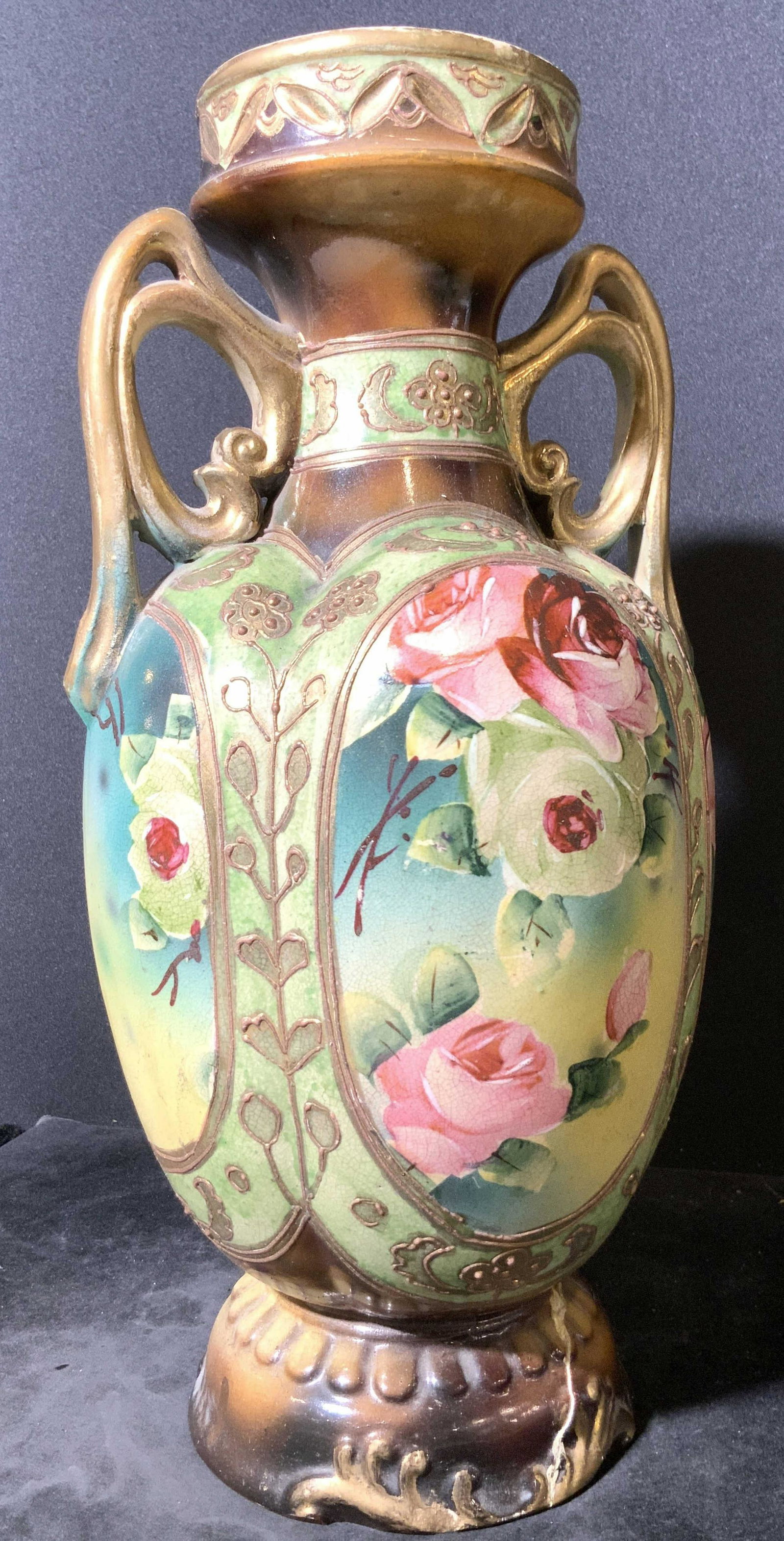 Vintage Hand Painted Floral Ceramic Vase: A vintage ceramic vase that has been hand painted with floral designs and nature motifs. In relief accents along all sides. Twin decorative handles feature pierced ceramic designs. Primarily green and