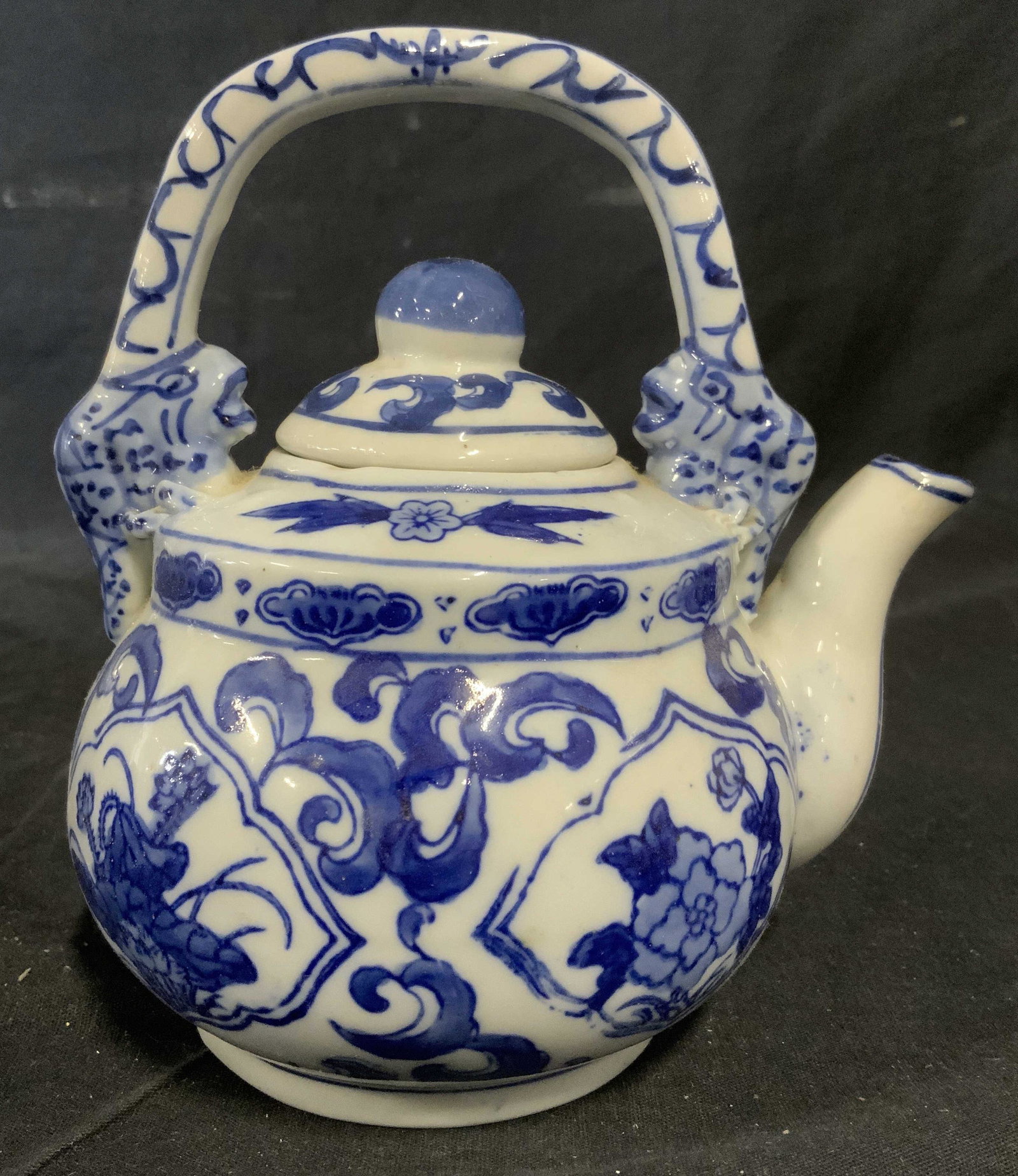 Vintage Asian Blue & White Ceramic Tea Pot: Vintage Asian ceramic kettle. Ceramic is glazed, appears to be hand painted. Depicts floral and leaf like patterns, the base of the handle resembles fish. Measures approx 6.25 inches and 6 inches W. W
