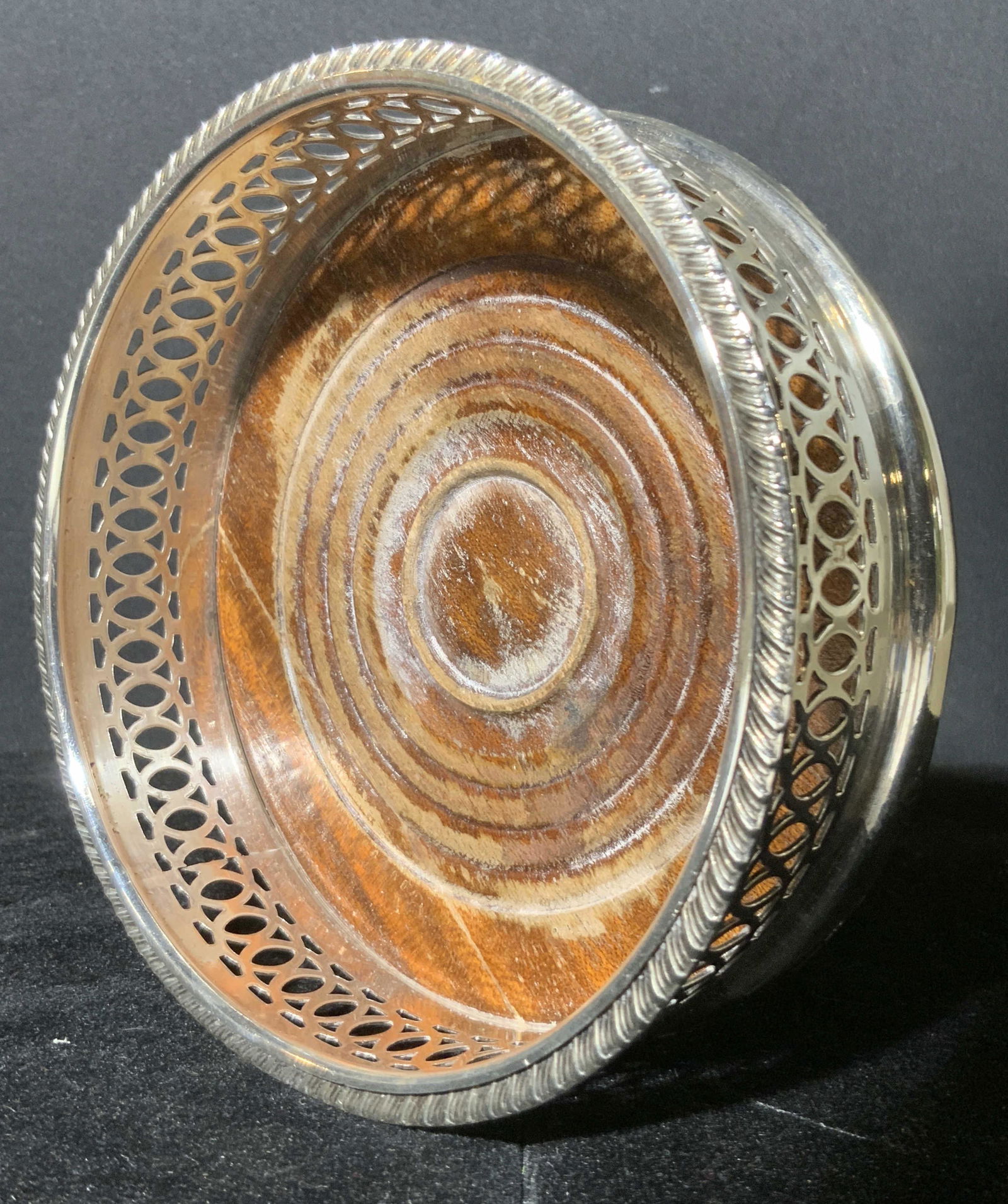 Vintage Silver tnd Metal & Wood Drink Wine Coaster: A pierced silver toned metal and wood drink coaster holder. The metalwork is polished and features Anne bossed design along the rim. The wooden center has carved accents. Underside possesses green fel