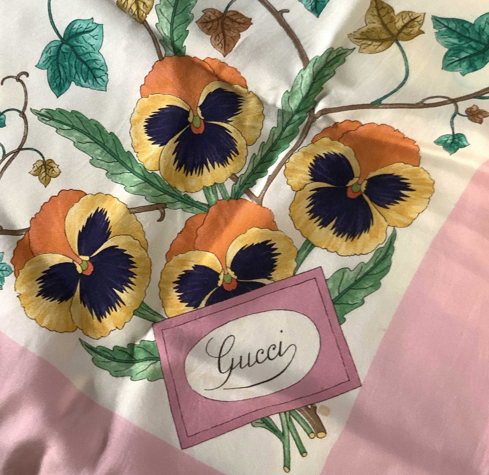 GUCCI Artist Signed Pink Floral Square Scarf: Floral and vine motif scarf with pink boarder. Flowers are all pansies in the colors pink, yellow, purple, red, and blue. Near the boarder it reads: GUCCI on one side and V. ACCORNERO. Mild discolorat