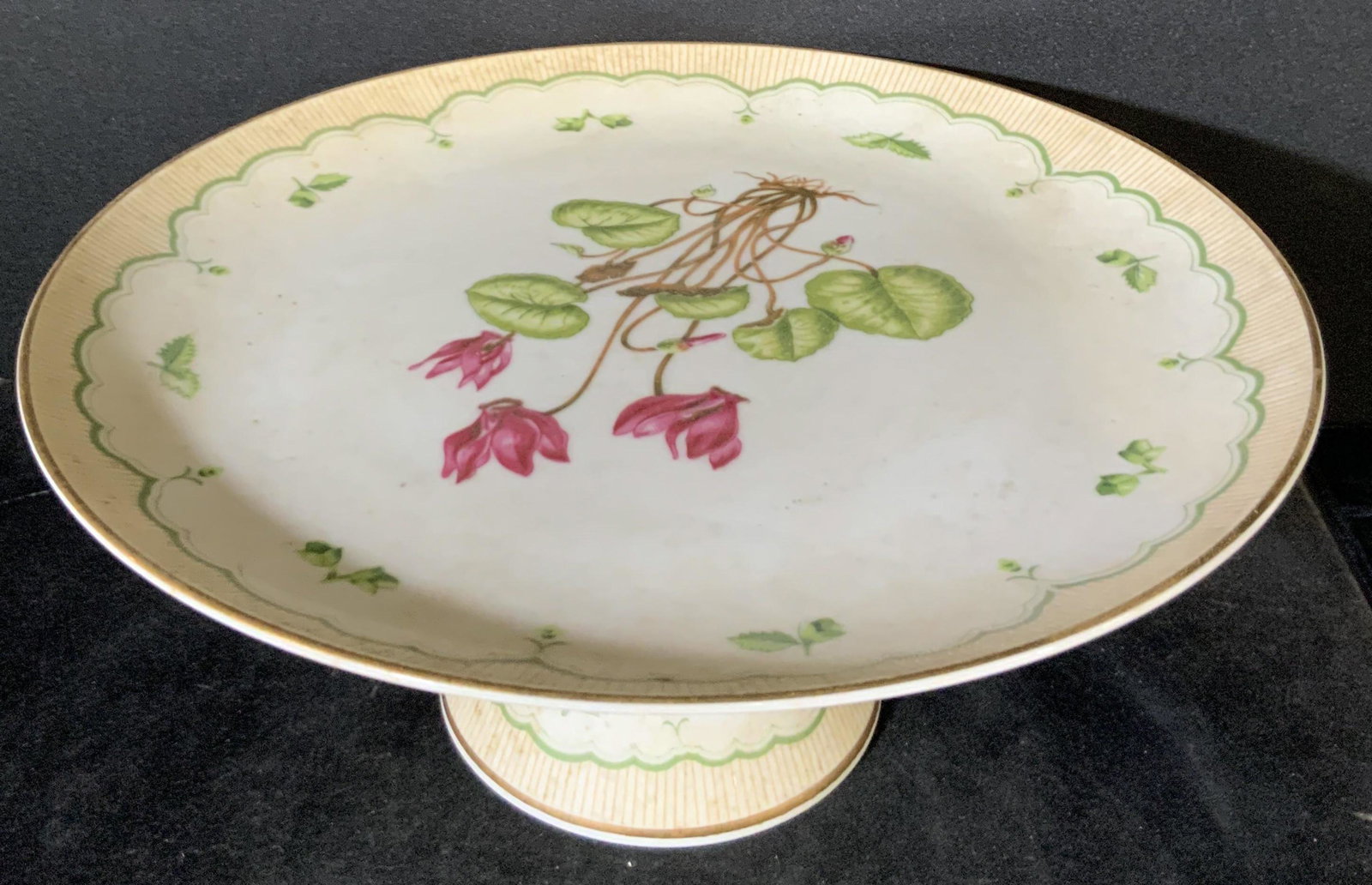 GEORGES BRIARD Sig. Victorian Garden Pedestal Dish: A porcelain pedestal dish featuring Cyclamen flowers and foliage designs. More flowers decorate pedestal. Gilt line work decorates the rims of the base and the dish. Some mild discoloration throughout