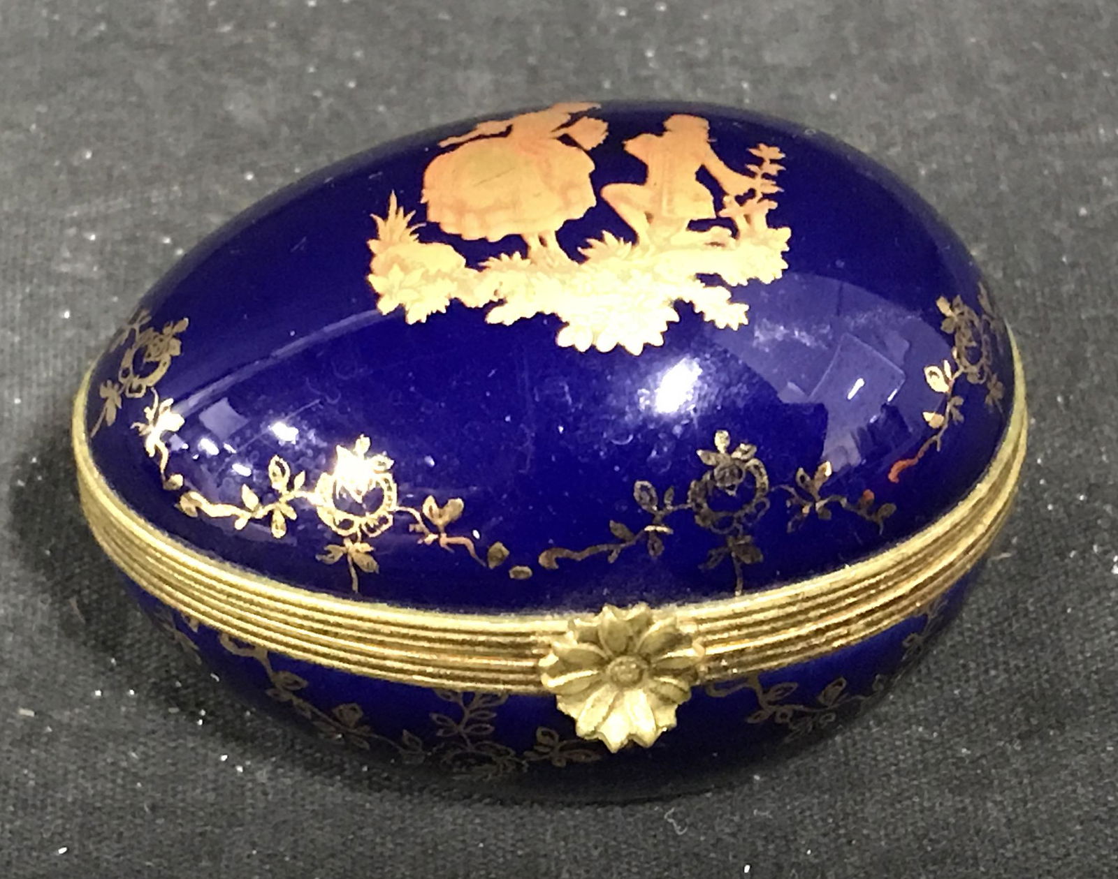 Limoges French Porcelain Egg Pill Box: Limoges French porcelain egg jewelry box, gold toned metal accents, painted royal blue with gold designs, label to underside reads ‘Limoges, Limoges Made in France’, floral gold tones metal clasp