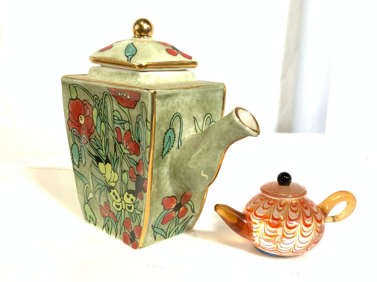 Lot 2 Petite Porcelain & Art Glass Teapots: Lot includes 1 porcelain teapot marked VAN GOGH MUSEUM ON UNDERSIDE and 1 art glass teapot with tag which reads LENOX on underside. Porcelain vessel has intricate multi toned floral vine and leaf deta