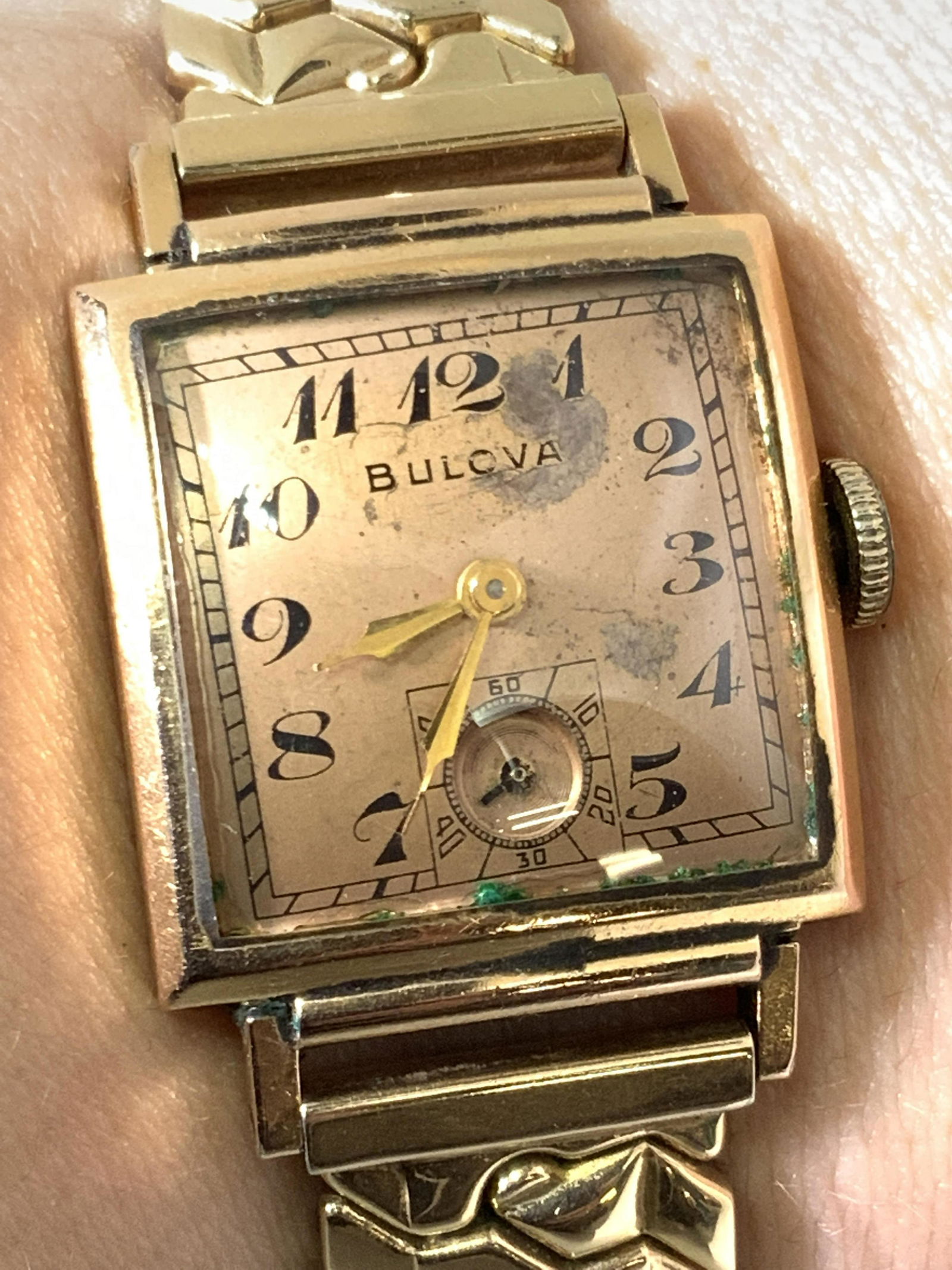 Vintage BULOVA Signed Stainless Steel Watch: Gold toned metal stretch watch with stainless steel backing. The piece is polished with a square watch face. Clock face reads BULOVA. Underside reads STAINLESS STEEL. Diameter approx. 2 in. Stretchy,