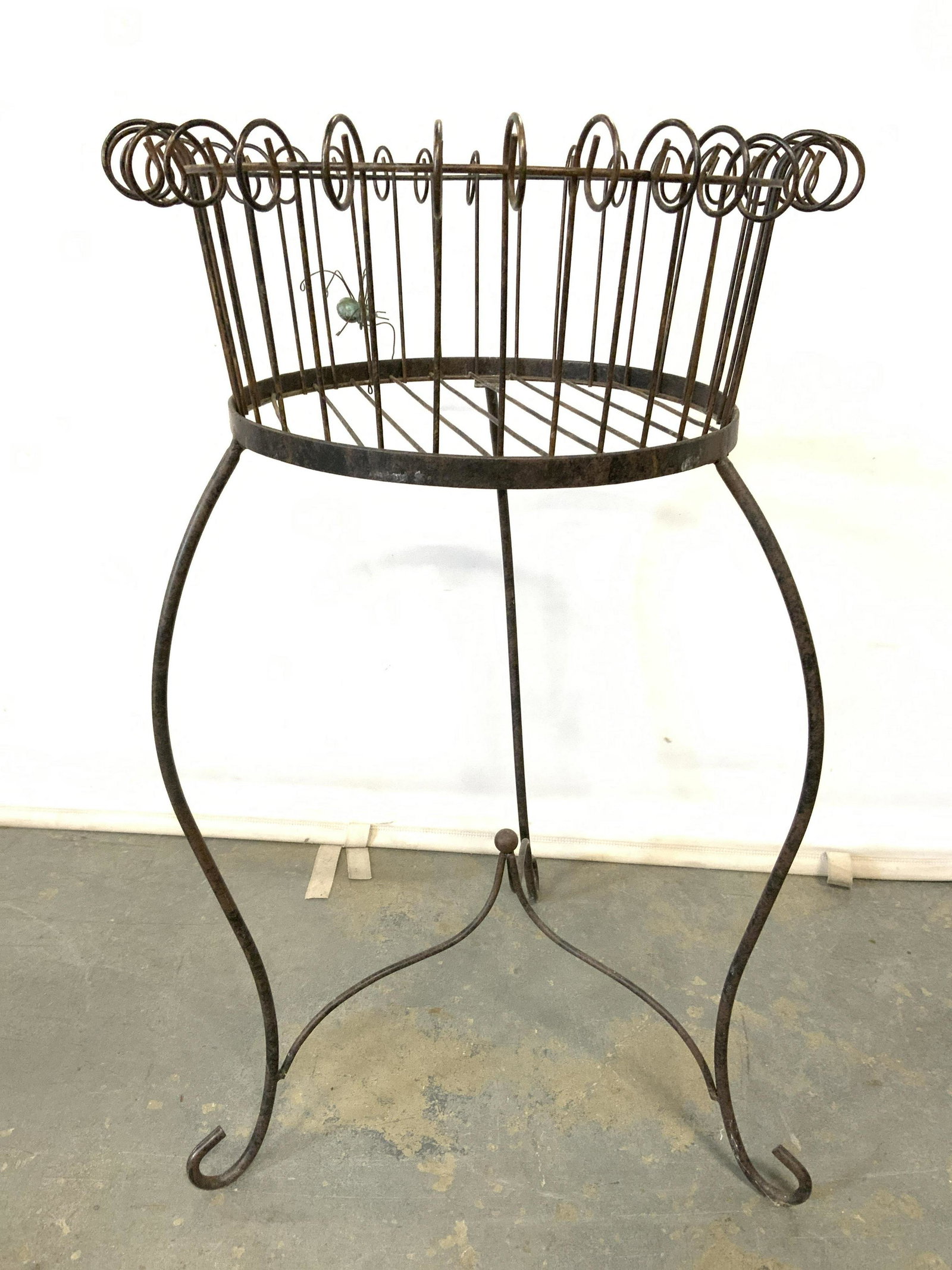 Vintage Metal 3 Foot Planter Stand: Planter stand is vintage possibly antique. Piece has 3 legs with curled feet. Legs have stretcher in between. Top of planter stand has metal spider figural. Piece measures approx 30 inches tall 18 inc