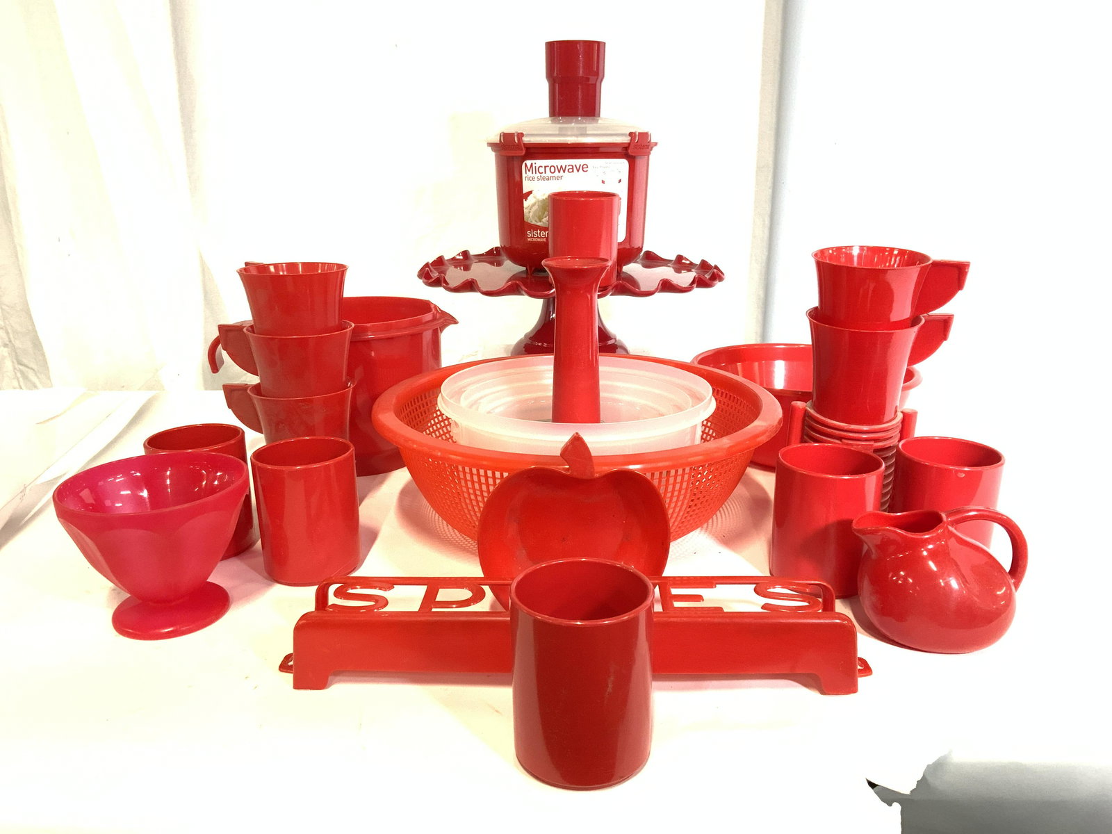 Lot 25 Retro Red Kitchen Supples, Utensils & More: Lot 25 retro red kitchen supplies. Utensils, serving pieces, accessories, and more. Pieces are crafted from plastics. Various sizes and shapes. Pedestaled Cake plate measures approx. 13 inches wide x 