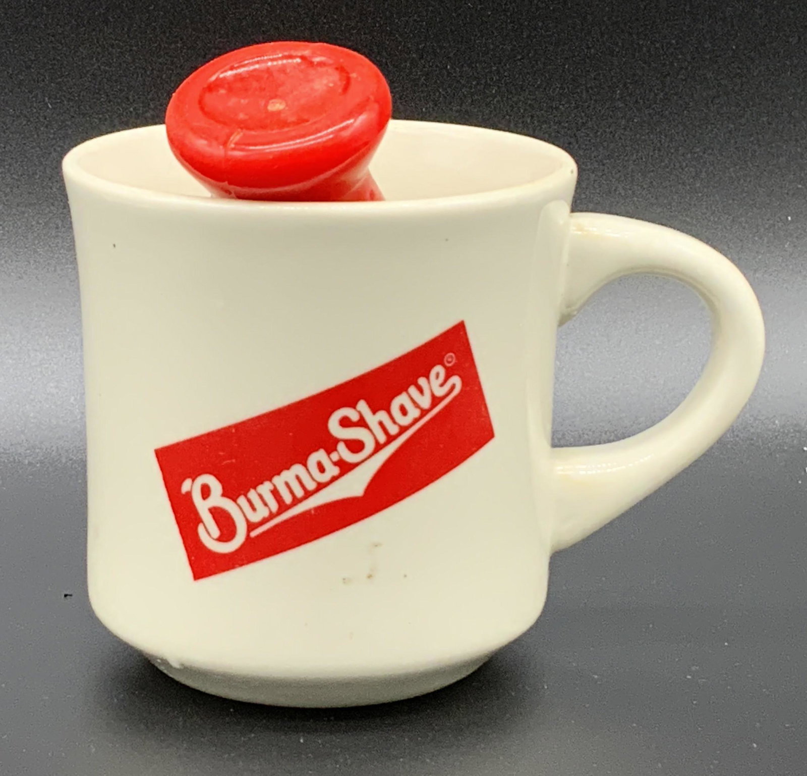 Pair Vintage BURMA SHAVE Mug & Brush, Collect: Collectible Burma Shave Mug and Brush set. The bristles of the brush are connected via a retro red handle. Handle crafted from composite material. The mug is white porcelain. The Burma Shave logo is p