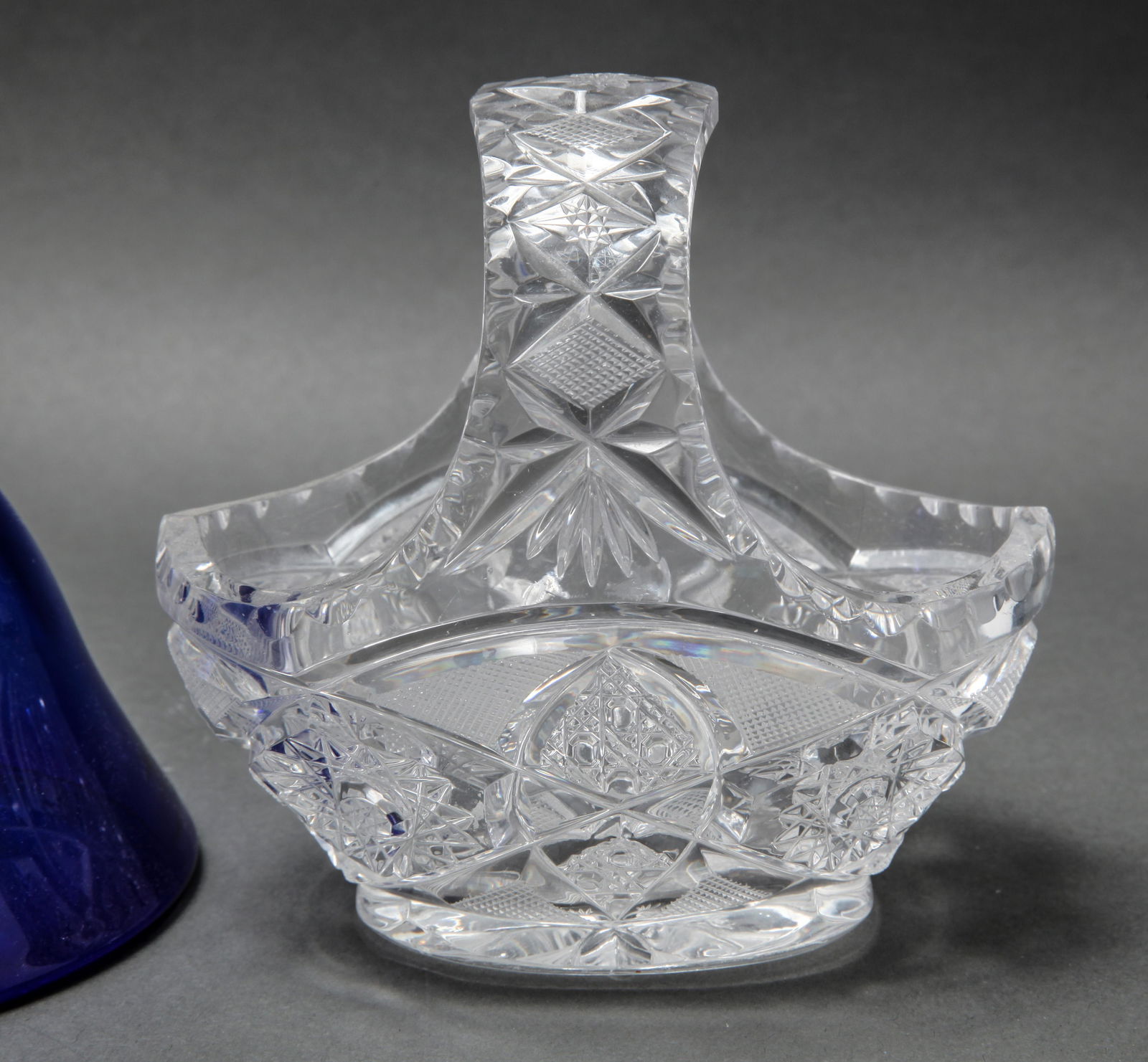 Clear And Blue Glass Group, 5: Clear And Blue Glass Group, 5 Group of glassware, comprising a cut crystal basket-form candy dish, two pressed glass votive candle holders, a frosted glass footed bowl with floral relief decoration, a