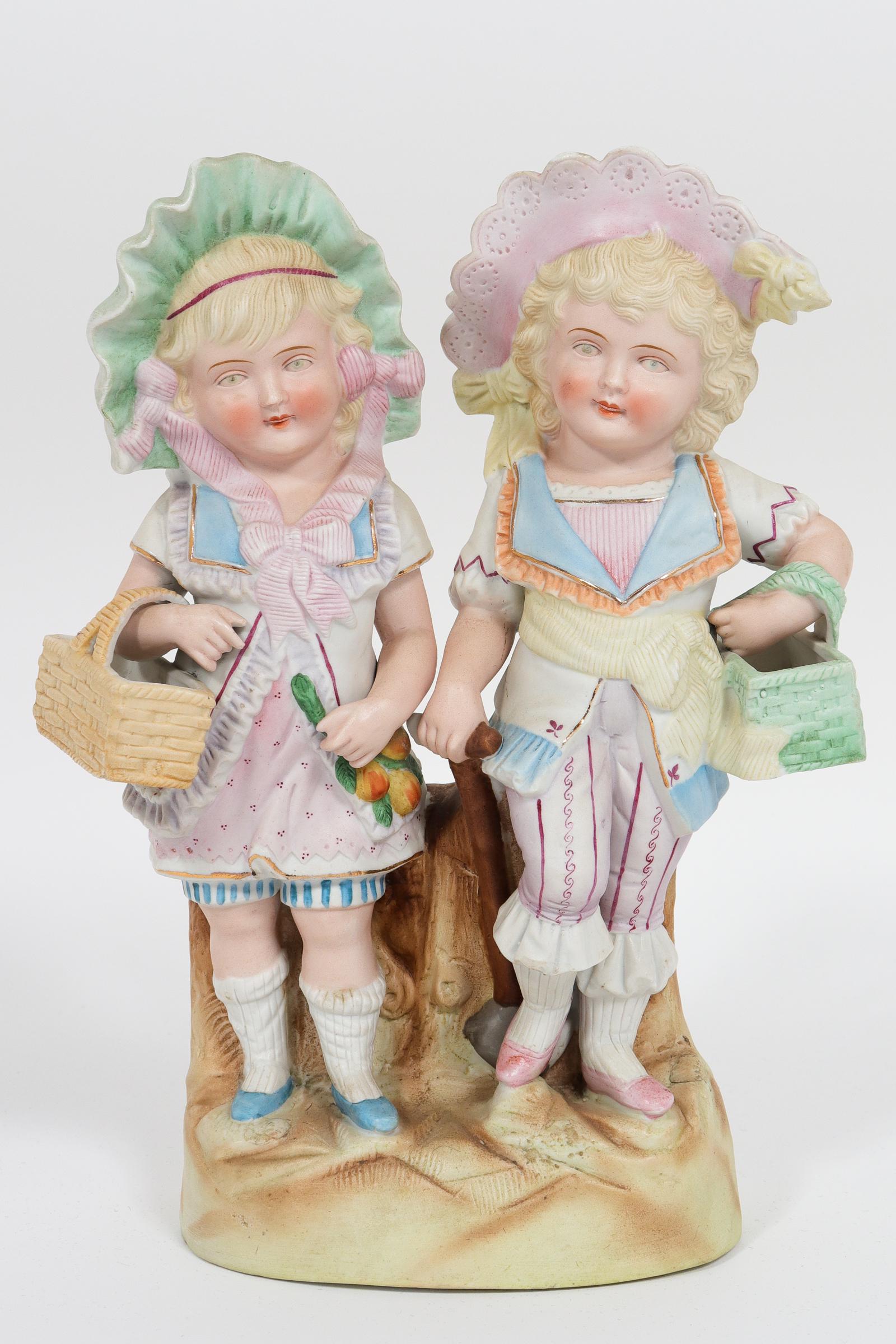 Continental Bisque Porcelain "Children" Group: Continental Bisque Porcelain "Children" Group Continental bisque porcelain figural sculpture depicting two twin girls holding baskets and wearing bonnets. 11.5" H x 8.75" W.