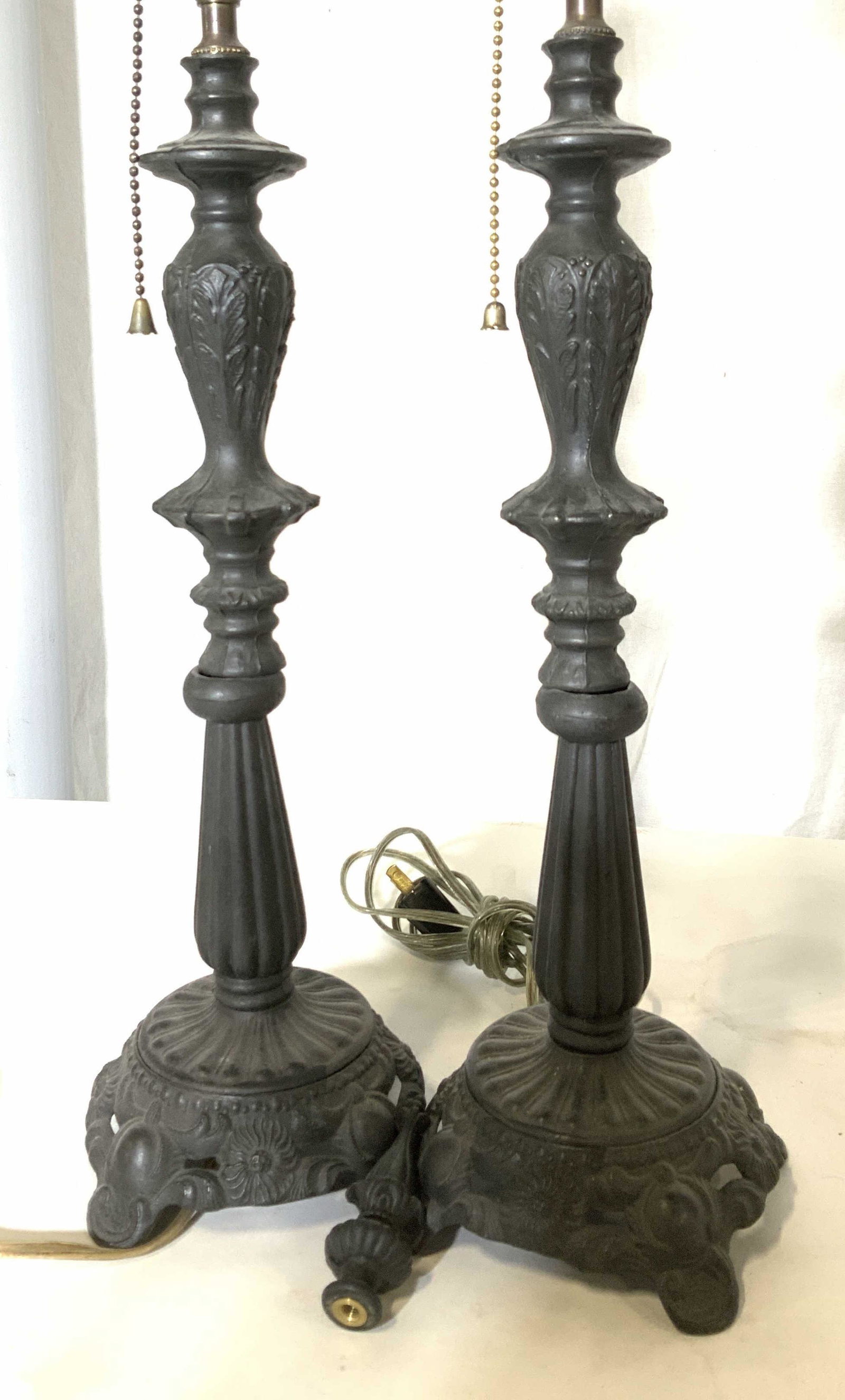 Pair Vintage Black Metal Victorian Style Lamps: Pair lightweight metal lamps, cast metal, embossed Victorian features. Pull chain on light socket, reads Leviton. Included are lamp harps and 1 finial. Ht 23 in. Base width 5 in. Victorian lamps, deco
