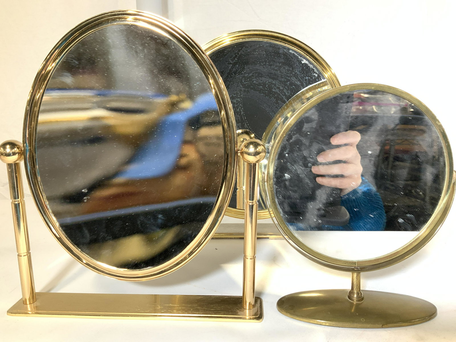 Lot 3 Vanity Top Brass Make Up Mirrors: Tabletop mirrors, in the style you see in department stores on jewelry and cosmetic counters. Brass or brass plated, swivel for close- up/ distance mirrors. Large round, medium oval, smaller round. Lr