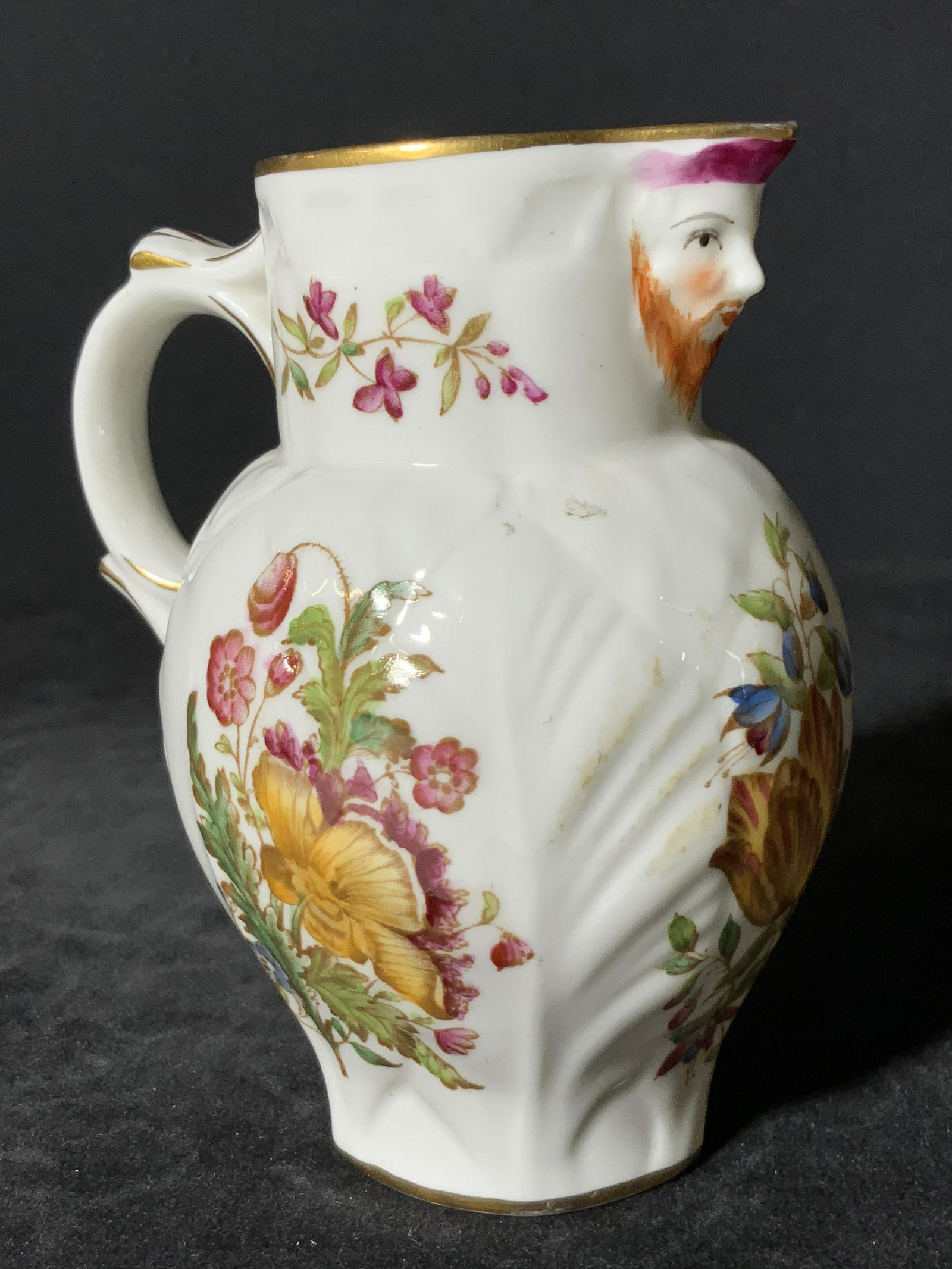 ROYAL WORCESTER Signed English Porcelain Creamer: A white porcelain creamer featuring hand painted designs and embossed porcelain accents. The spout of the creamer has been painted to depict a bearded man’s face. Across the body of the creamer ther