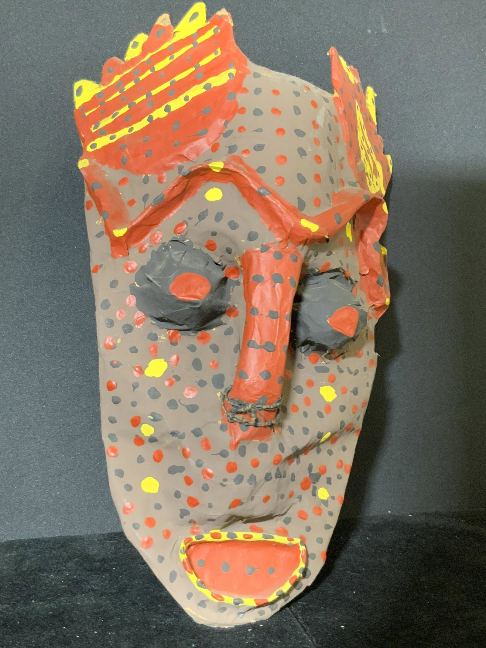 Handmade Papier-Mâché Folk Art Mask: A handmade and painted tribal folk art mask. Piece is crafted from papier-mâché. Underside has metal wire for displaying. Approx. 14L x 7W in. Tribal mask, primitive mask, papier-mâché, paper mach
