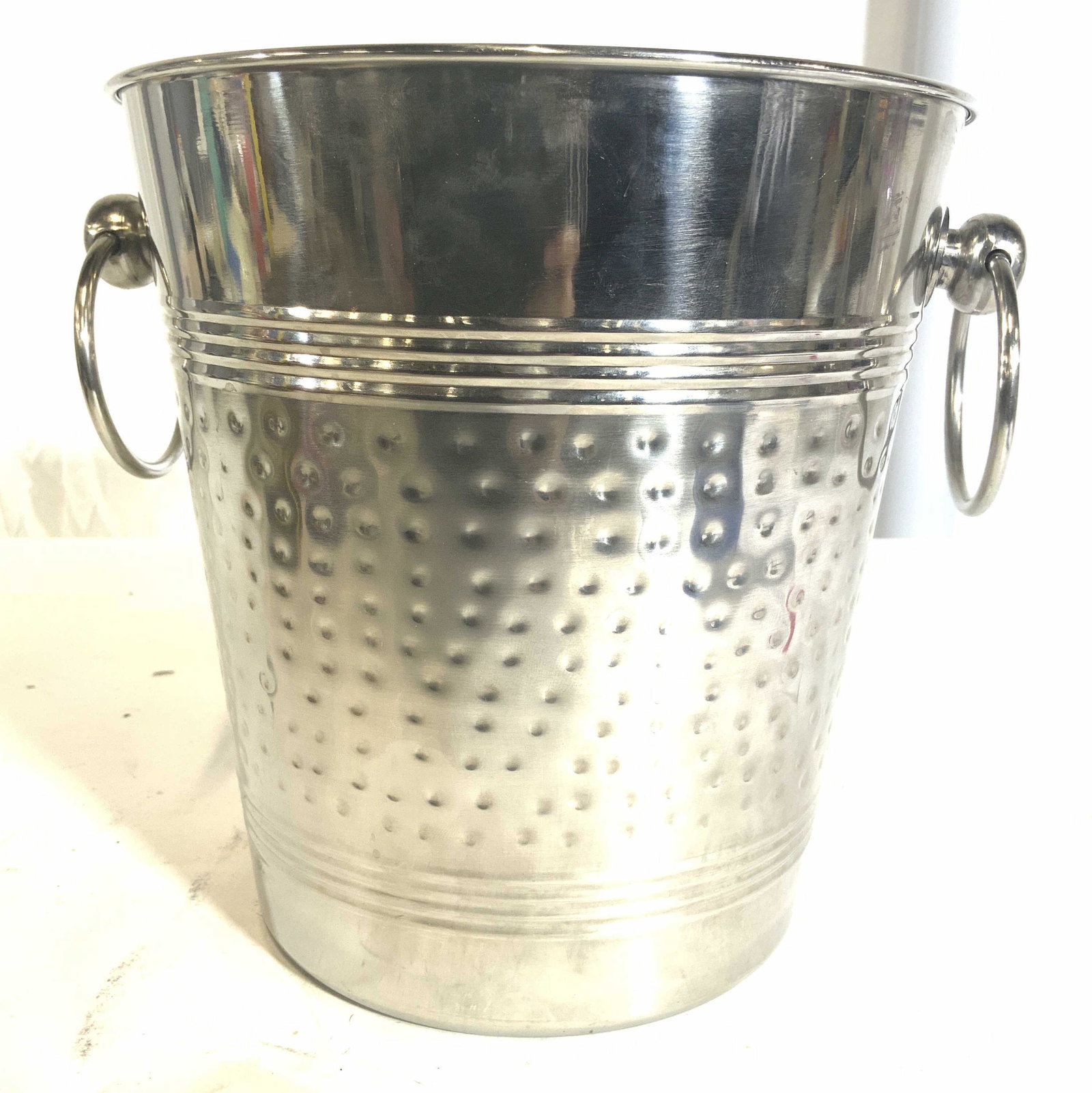 Metal Wine Cooler Ice Bucket W Handles: Ice bucket is silver toned & metal. Piece has 2 dangling circular handles. Center of piece has dimple detail. Piece measures approx 8.5 inches tall 9.5 inches wide with handles. Ice bucket, champagne 