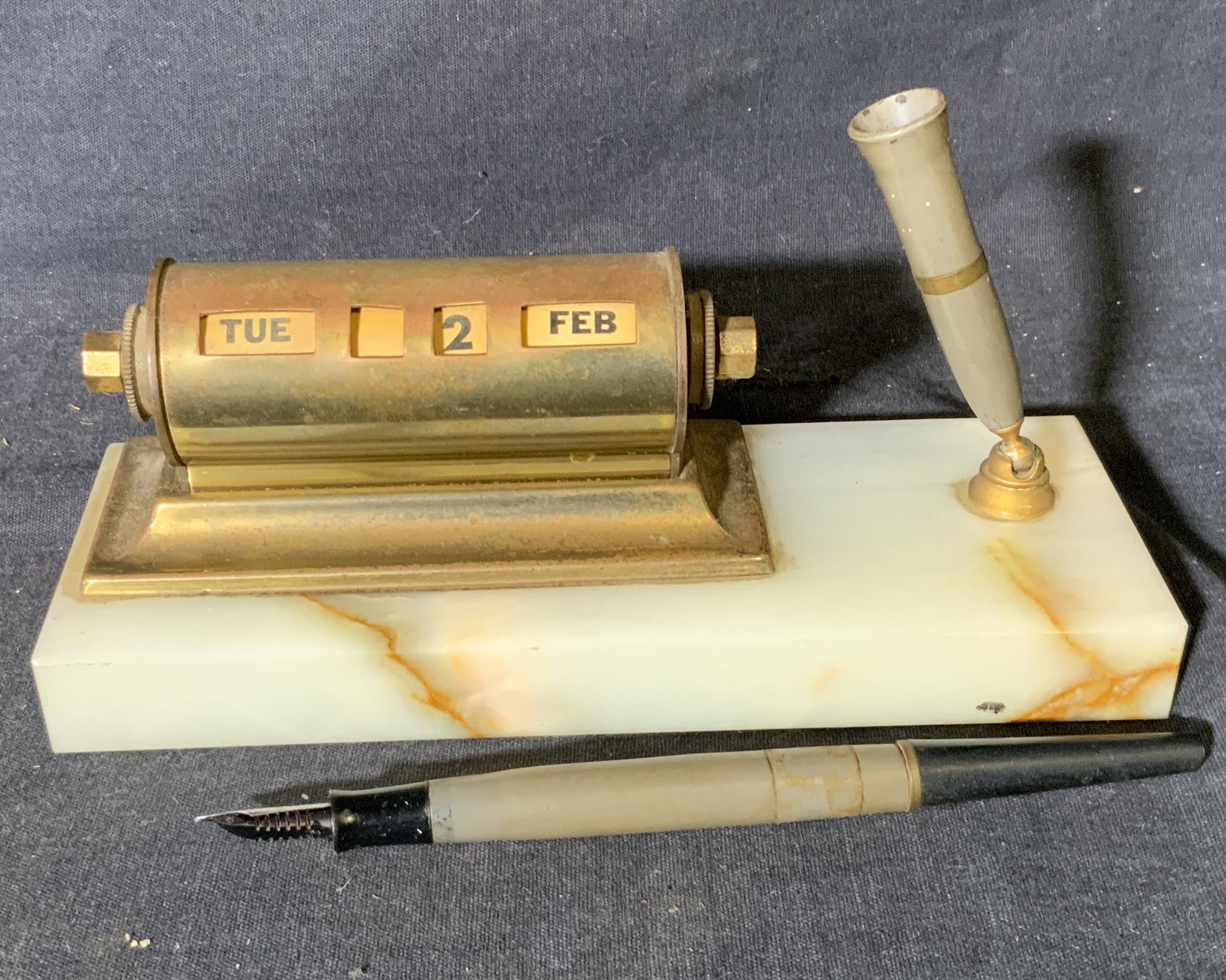 Group Lot 3 Desk Accessories: Group lot 3 desk Accessories, lot includes a pen holder/date reader a ruler and a letter opener, letter opener shaped like a sword, ruler made of composite reads ‘The Army’s giving guarantees, mea