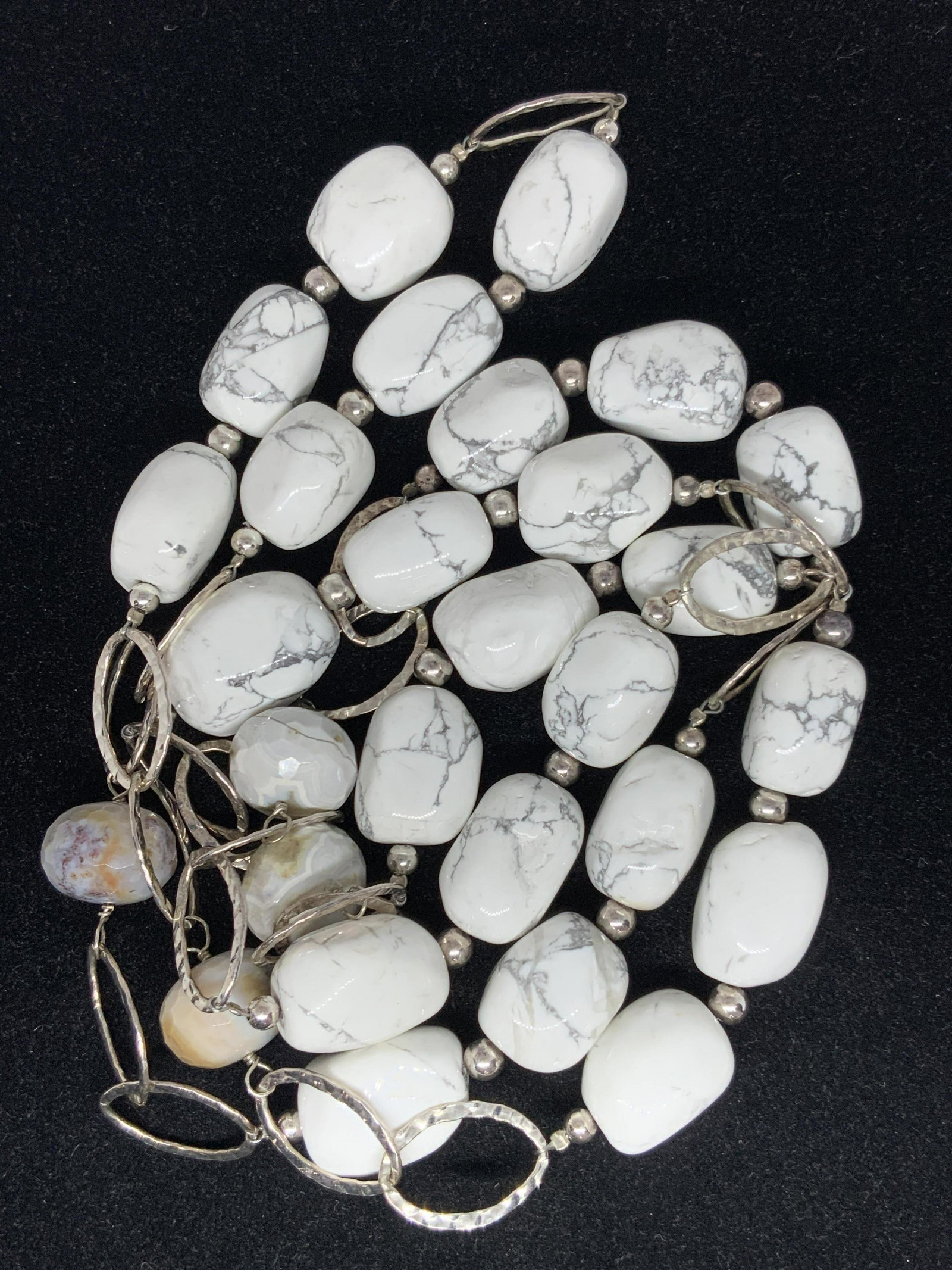 Glass Marbled White Bead Opera Necklace, Jewelry: A opera length necklace consisting of white marbles glass beads and hammered silver tone metal ovals. The beads are in various shapes, similar sizes. Four of the beads are a deeper grey, off white col