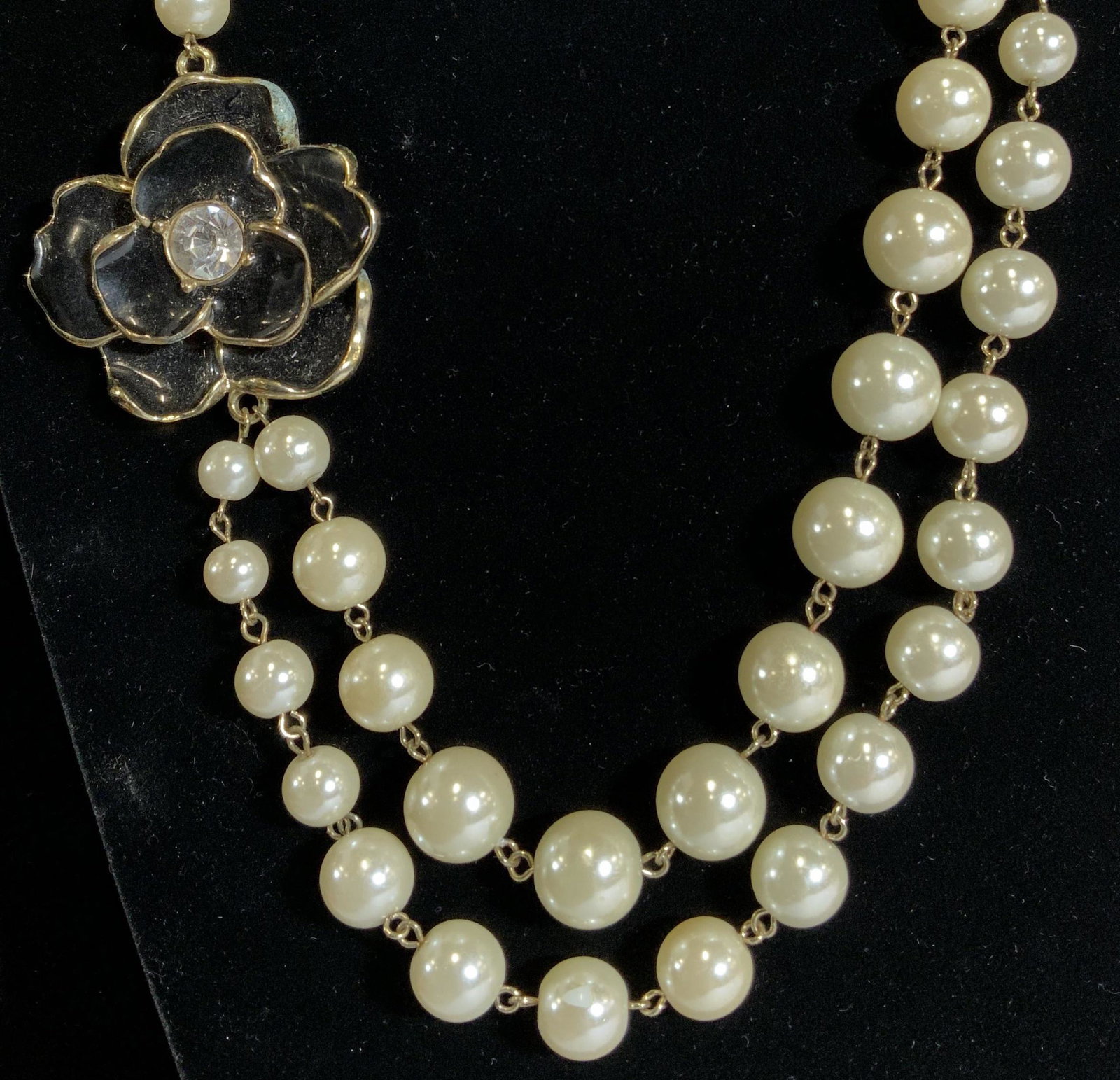 BIJOUX TURNER PEARL & Flower Enamel Necklace: Costume pearl necklace, double strand with sizable beads, 14mm to 9 mm. Off center 1 3/4 in black enamel flower with center rhinestone. Adjustable chain. 20 in. Longest length. Signed charm reads Bijo