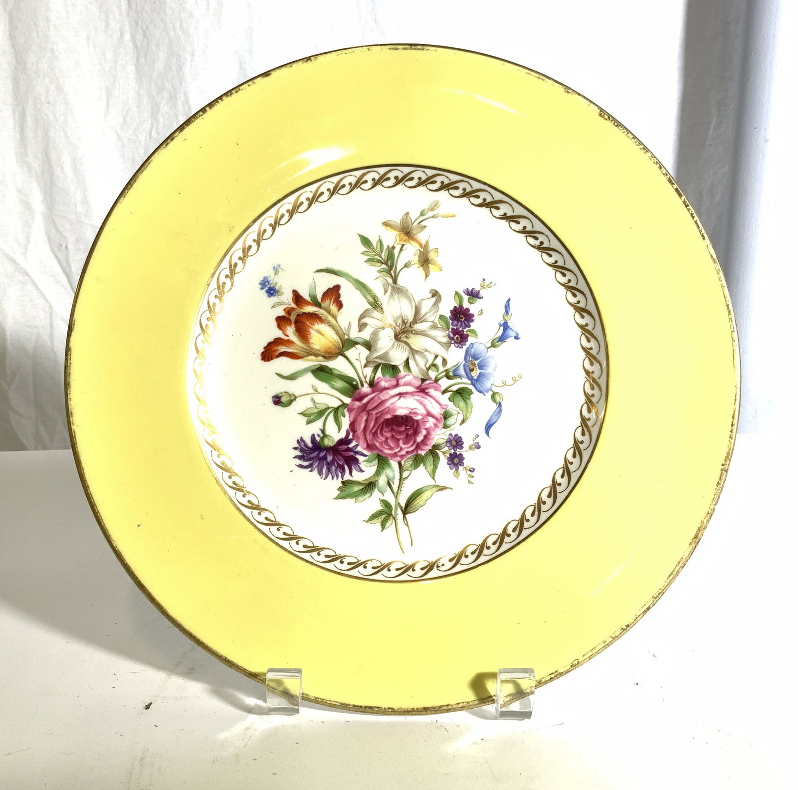 ROYAL WORCESTER English Porcelain Plate: Underside of piece is marked ROYAL WORCESTER MADE IN ENGLAND. Piece has multi toned floral and leaf detail in center, yellow inner rim and gold toned rim edge. Piece measures approx 10.5 inches diamet