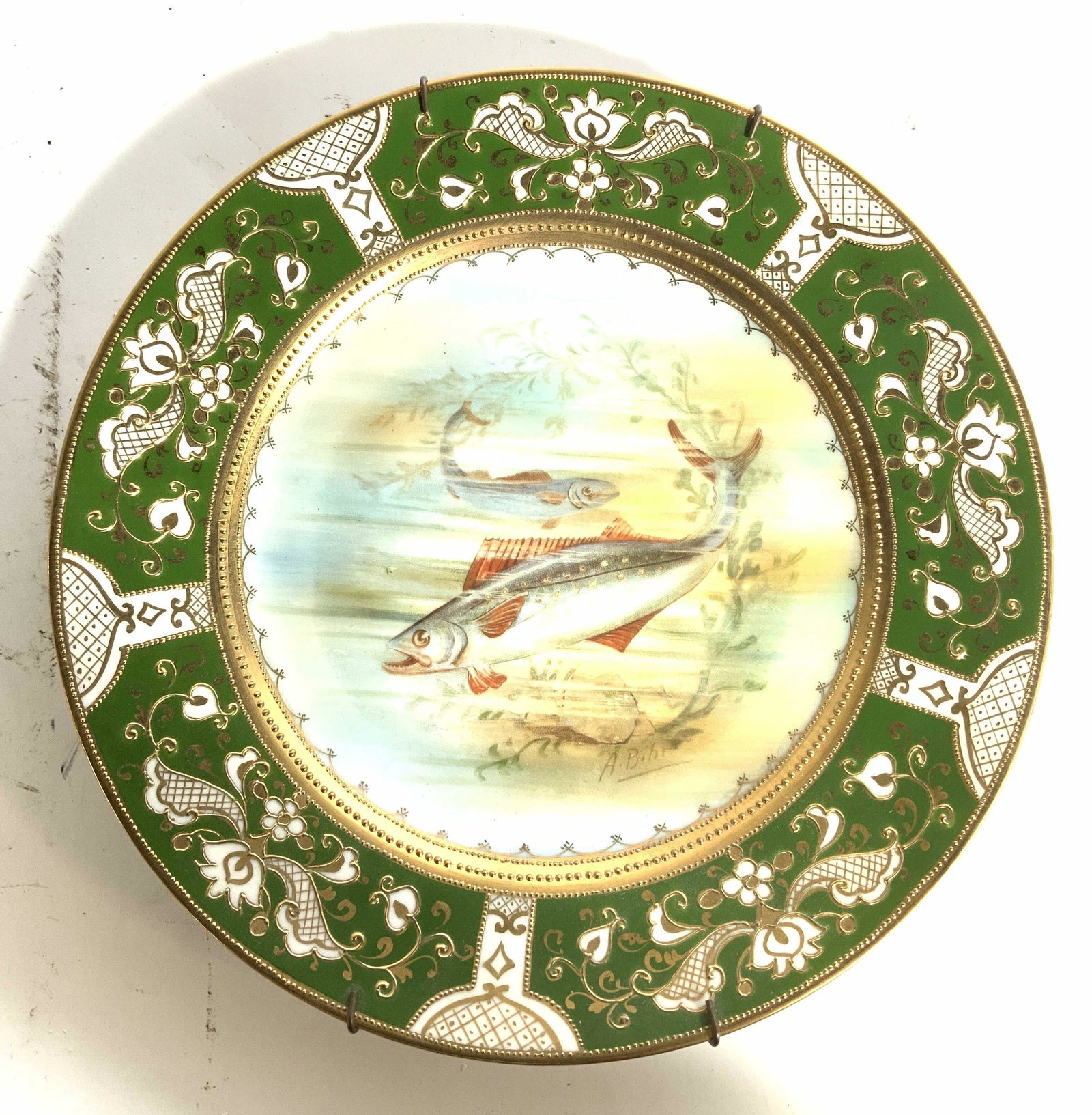 NIPPON Hand Painted Ornate China Plate: Underside of piece is marked NIPPON HAND PAINTED. Center of piece has depiction of fish. Dish has hand painted elements. Rim has white green & gold toned ornate detail. Piece appears to possibly be vi