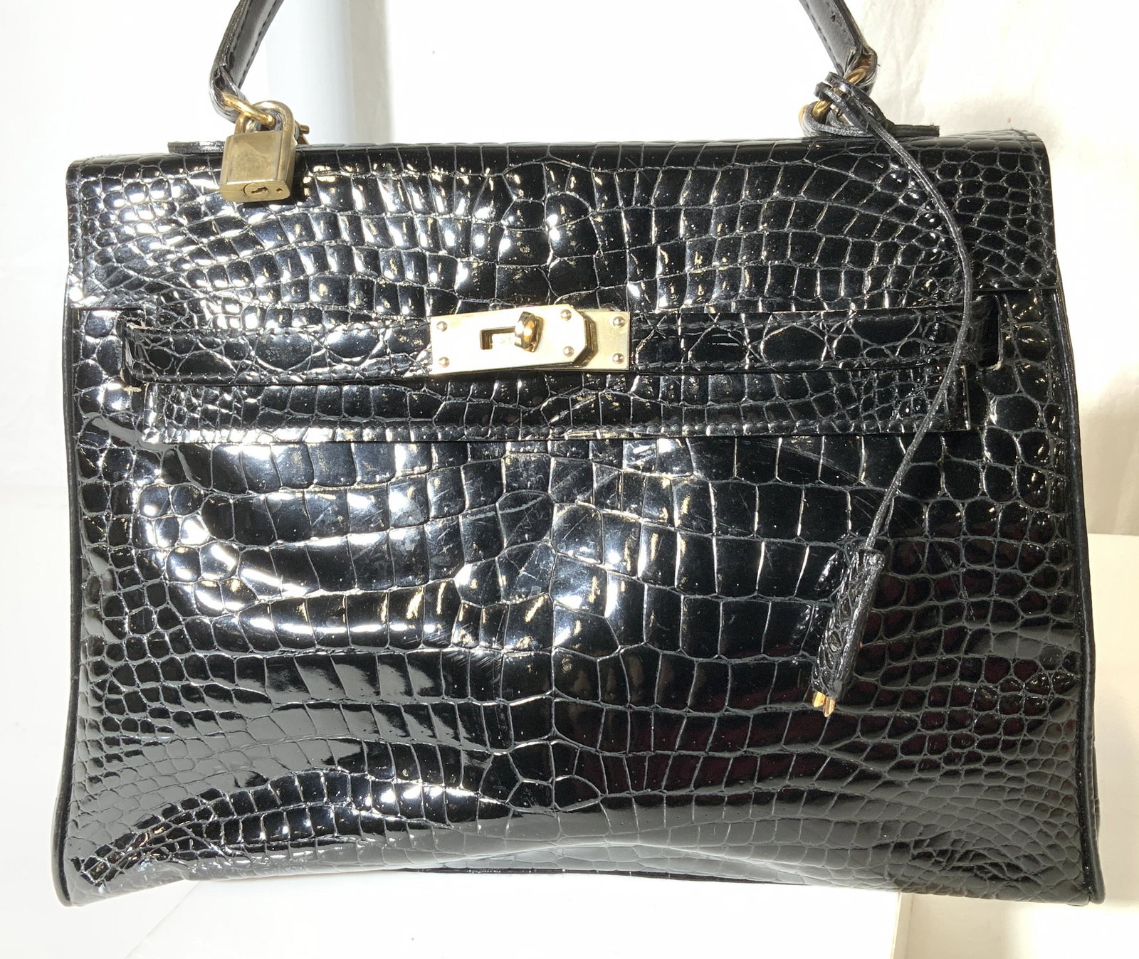 Black Leather Croc Handbag Purse: Handbag and shoulder bag with croc exterior detail and soft hand leather interior. Accented with lock and key, brass hardware, detachable strap, several inner compartments. 11.5 in L, 9.5 in. Ht, 4.5 