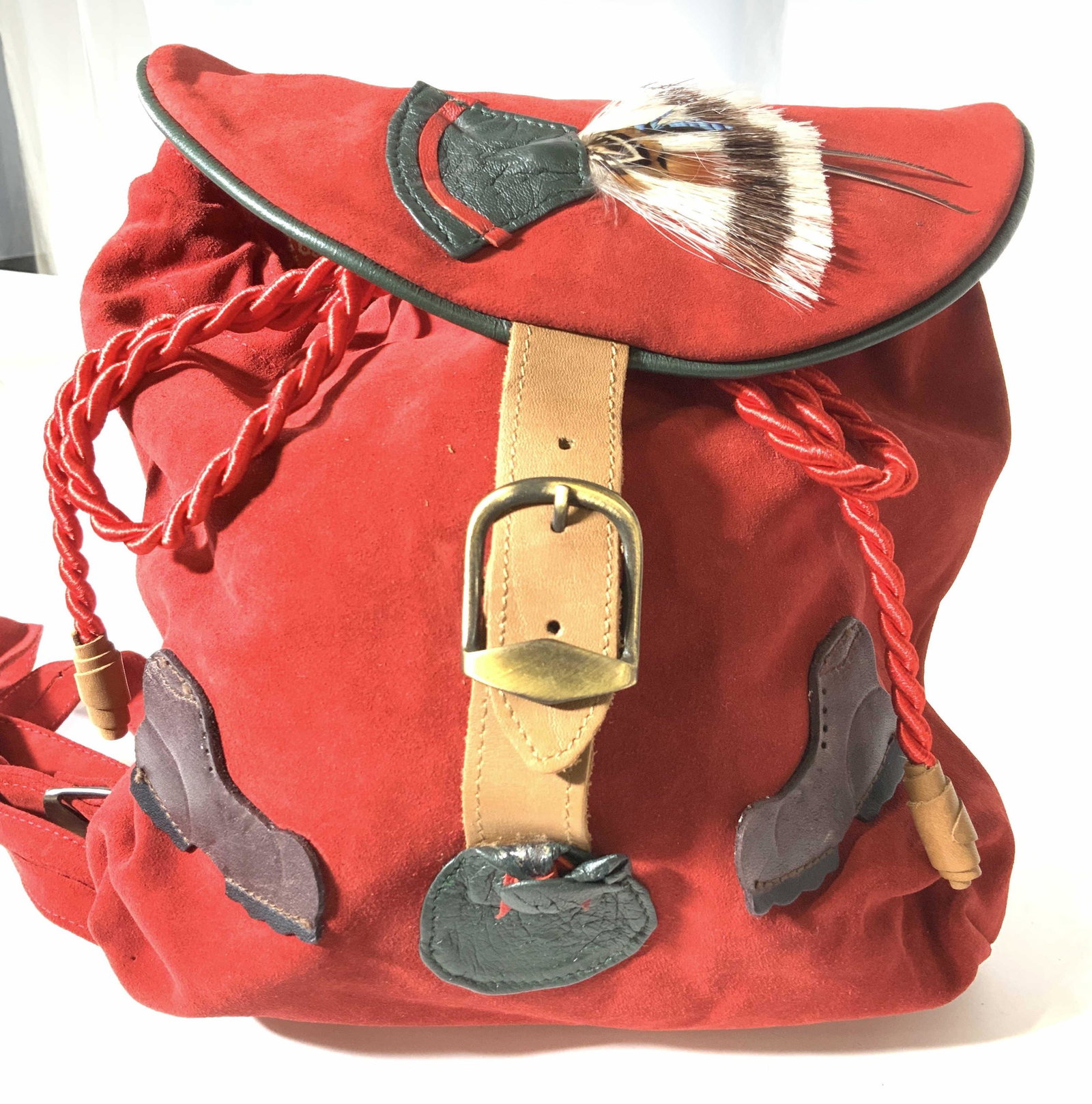 Handmade Red Suede Modern Knapsack: Modern Knapsack, appears never used, still with plastic tag ring on strap. Leather buckle and cinch rope closure with appliqué leather boots and Native American style feather on flap. Interior red an