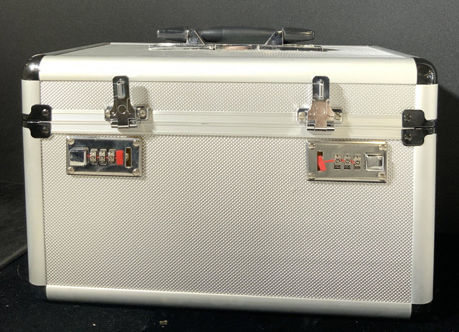 Portable Silver Tone Metal Keepsake Box: A silver tone metal keepsake storage box. The piece is crafted from metal and composite materials. Black handle on the lid. Appears to secure with a locking mechanism. Can also open by sliding the rai