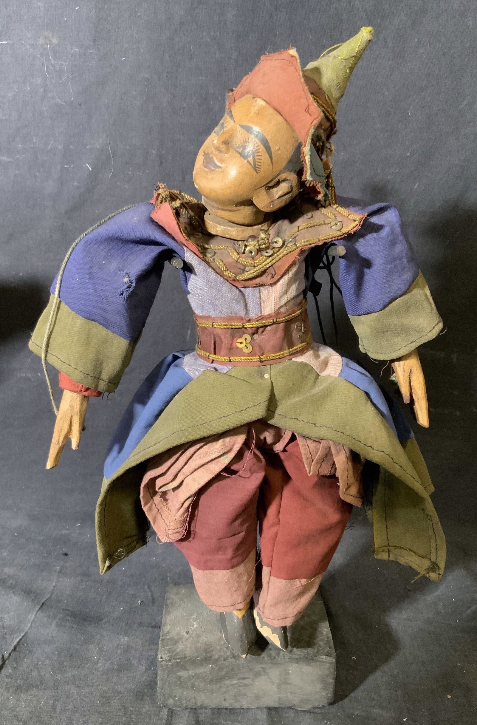 Wooden East Asian Puppet: Wooden East Asian Puppet, no apparent inscriptions or markings, puppet held up on a wood and metal holder, puppet has a wooden head and limbs, wear blue green and red clothes, puppet on stand measures