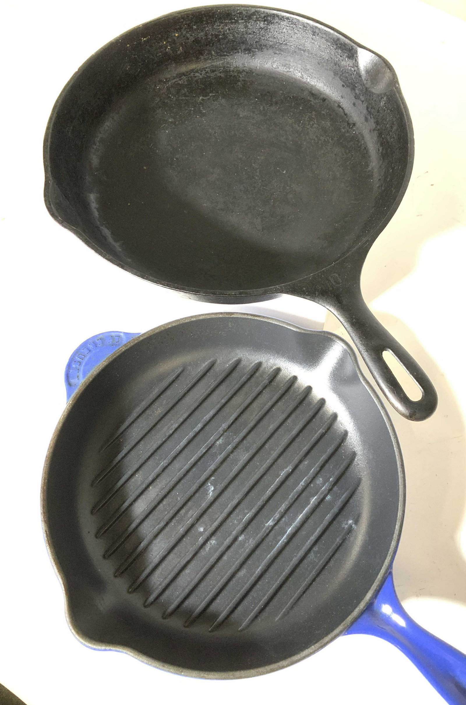 Lot 2 Iron Skillets, Le CREUSET: LE CREUSET ENAMEL AND IRON Skillet with original sticker label, made in FRANCE. Allows fat to drain and has side spouts to easily dispense. 10.5 in. Diameter. Total length 17 in. 11.5 in. Vintage cast