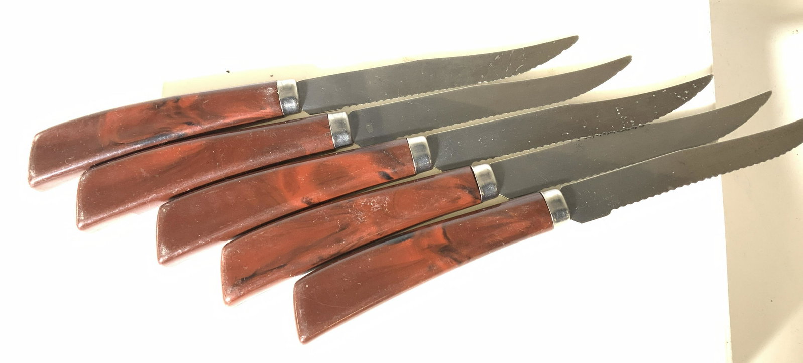 Set 5 Bakelite Handle Stainless Serrated Knives: Vintage everyday stainless steel serrated knives to be used for steak to bread and butter with marbled Bakelite handles. App 7.75 in. Long. Some Hallmarked Outrut. Property of Manhattan Estate. Mid ce