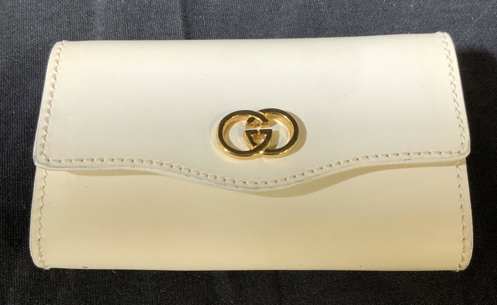 GUCCI Wht Leather Key Case, Org Tag, Italy: Gold tone interlocking G on white calfskin leather, impressed with Gucci Italy logo on interior, 6 looped secure hooks for keys or other needs. Snaps closed. Original ticket attached. Measures 4 x 2.2