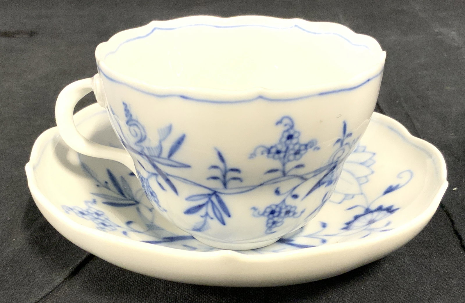 Set 2 Vintage MEISSEN Porcelain Cup & Saucer: Undersides of each piece has MEISSEN LOGO and is marked GERMANY. Lot includes 1 teacup & 1 saucer. Each piece is white with blue toned floral leaf & vine detail. Saucer measures approx 5.5 inches wide