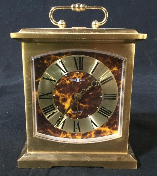 Vintage HOWARD MILLER Quartz Clock: Vintage HOWARD MILLER Quartz Clock. The piece is crafted from what appears to be brass, there is a marble pattern printed on the face of the clock. The piece measures approx 6 inches H, 4.6 inches W, 